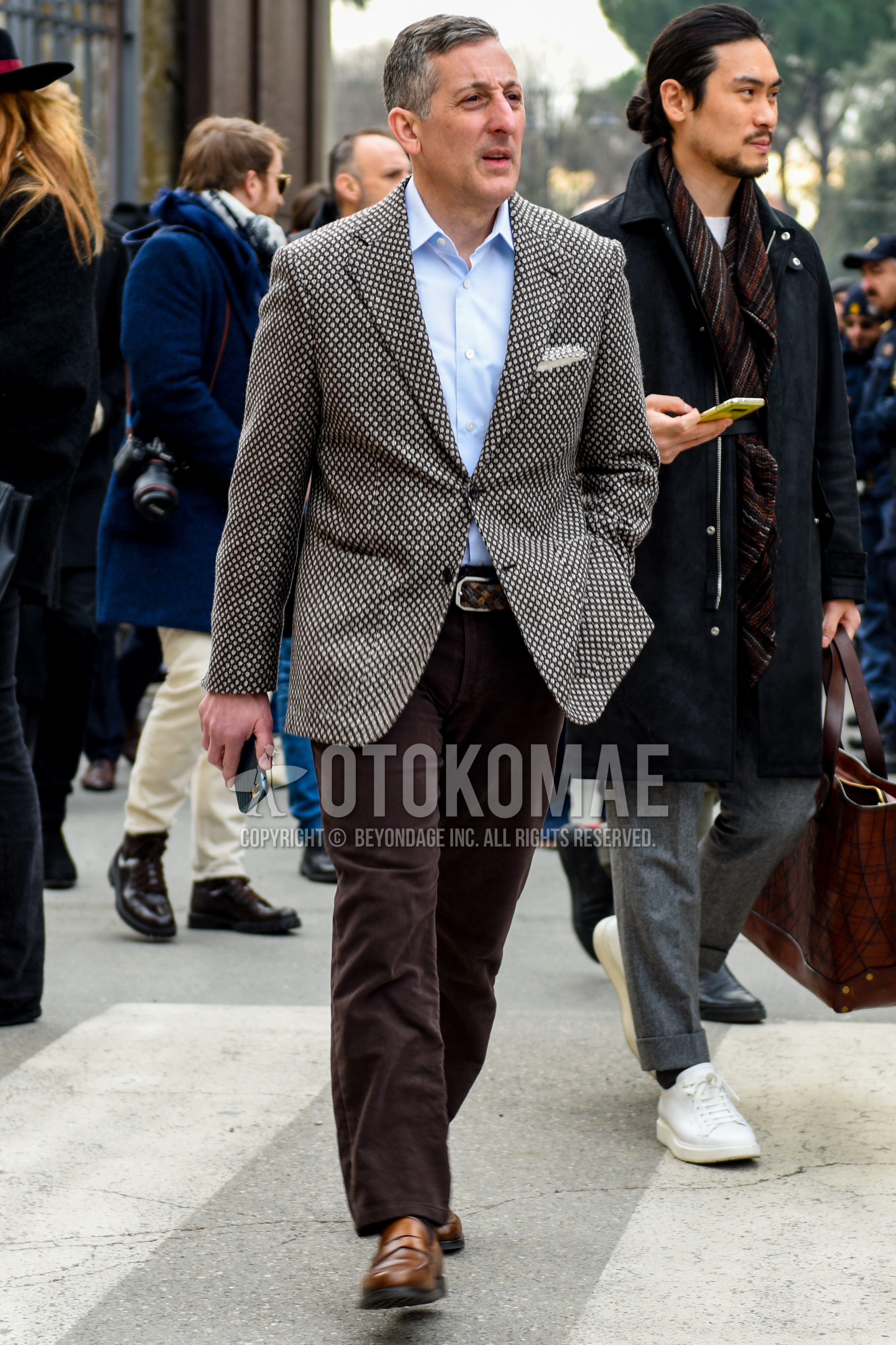 Men's spring autumn outfit with white black outerwear tailored jacket, light blue plain shirt, brown plain leather belt, brown plain slacks, brown coin loafers leather shoes.