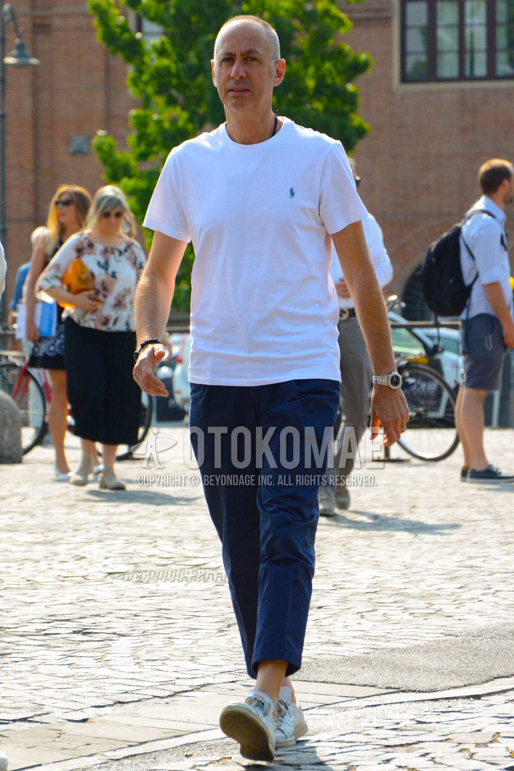 Men's summer outfit with white one point t-shirt, navy plain ankle pants, white low-cut sneakers.