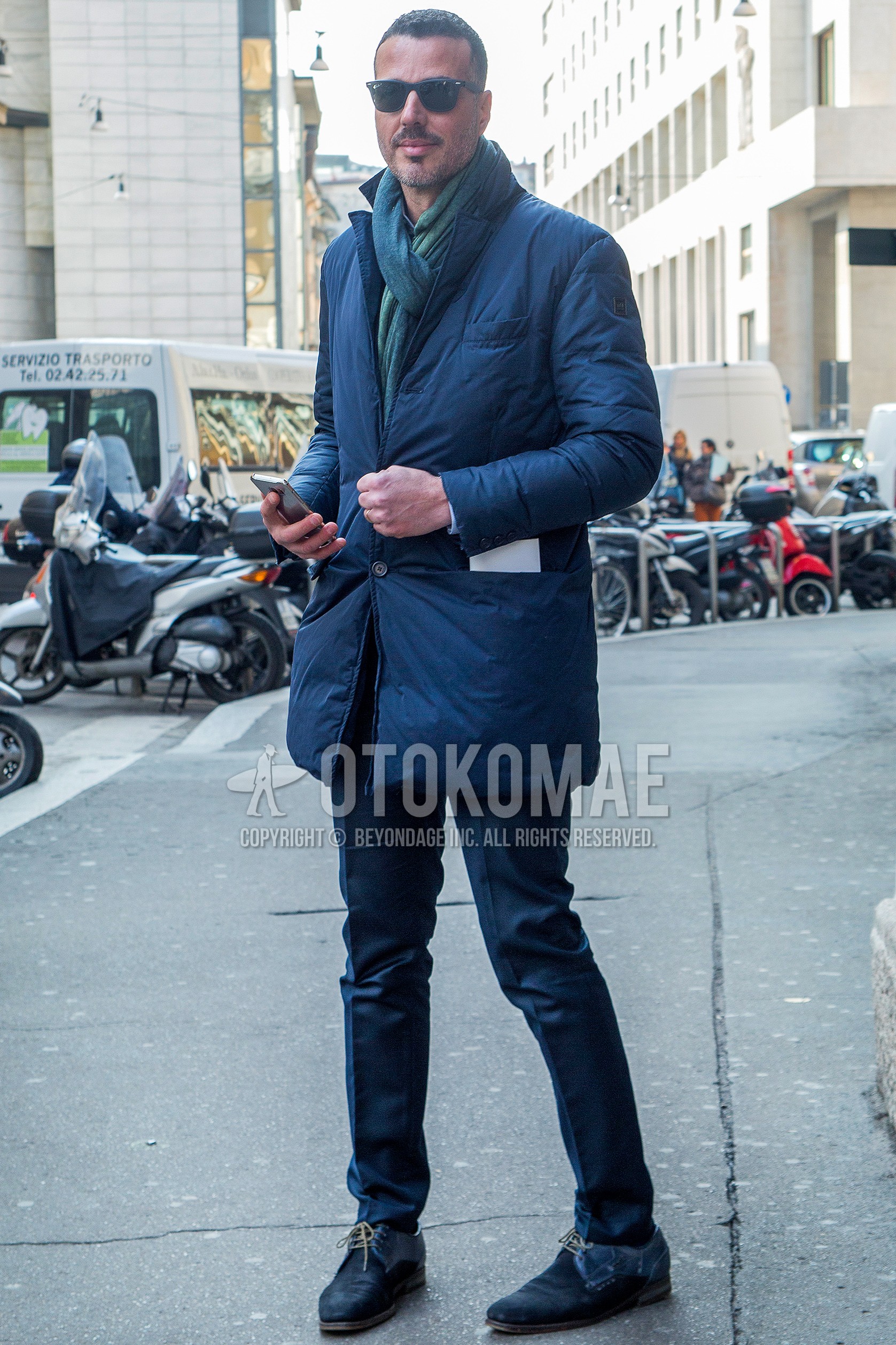 Men's winter outfit with plain sunglasses, green plain scarf, navy plain chester coat, navy plain slacks, navy plain toe leather shoes.