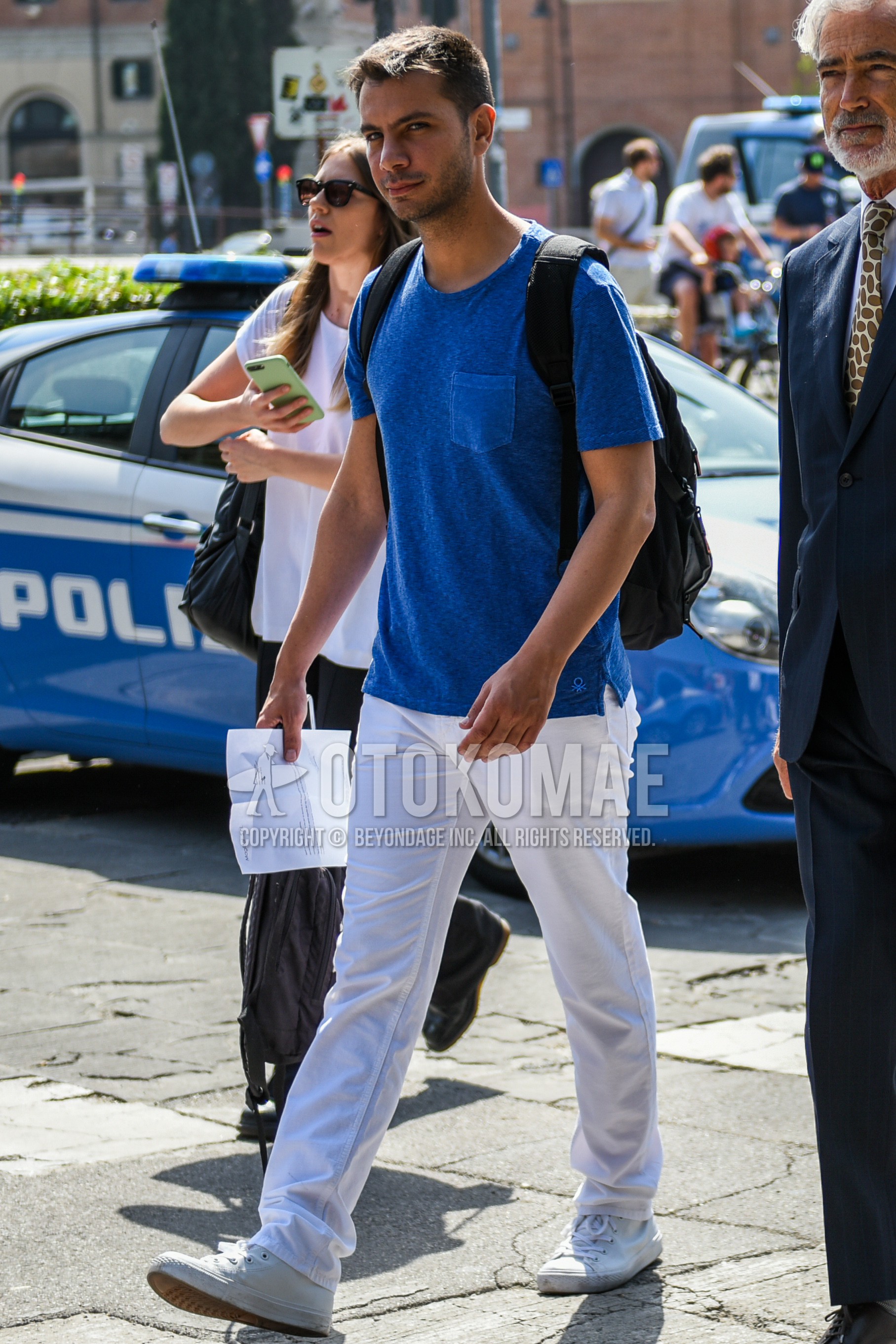 Men's summer outfit with blue plain t-shirt, white plain cotton pants, white low-cut sneakers.