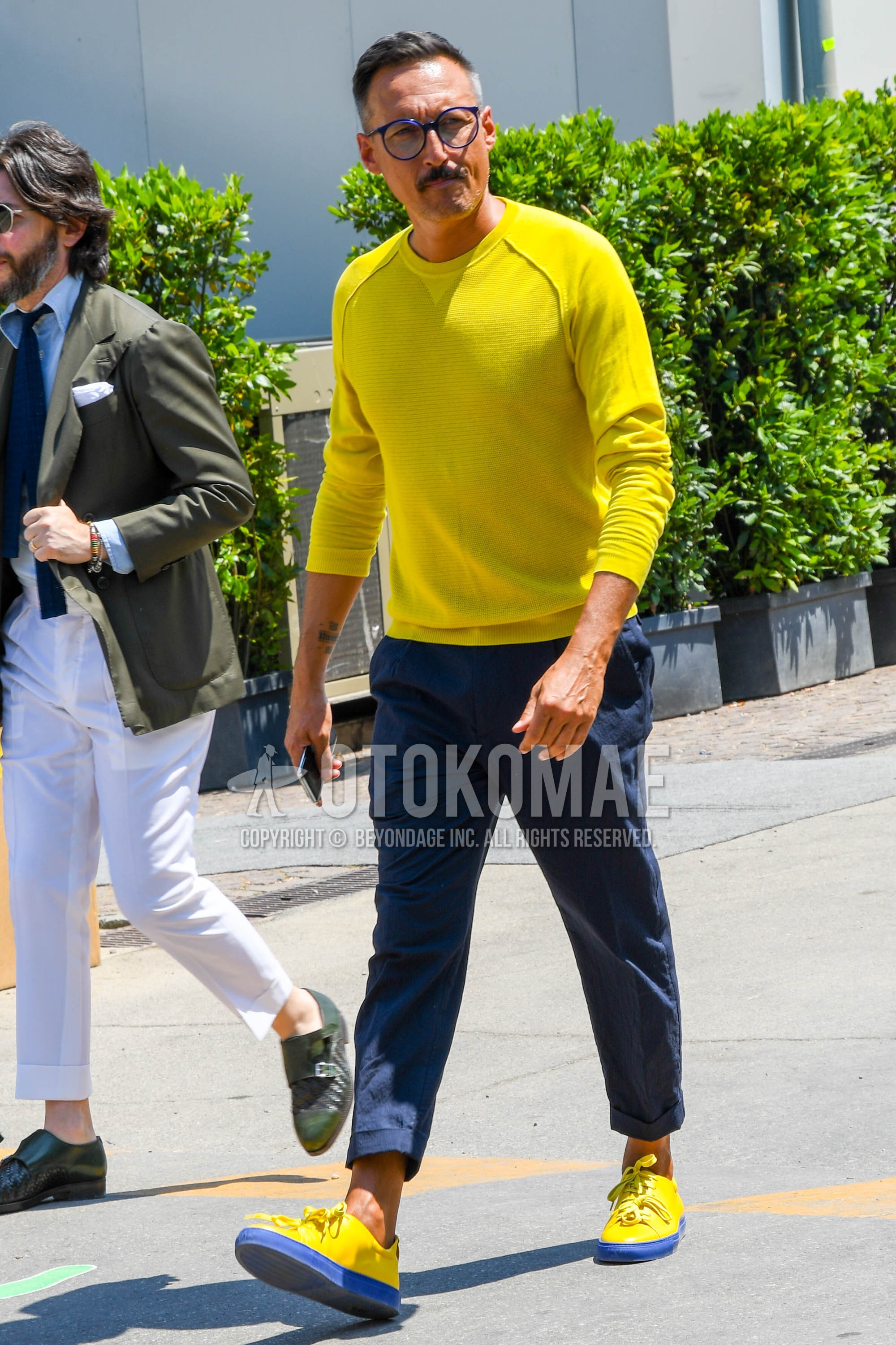 Men's spring autumn outfit with plain glasses, yellow plain sweater, navy plain cotton pants, yellow navy low-cut sneakers.