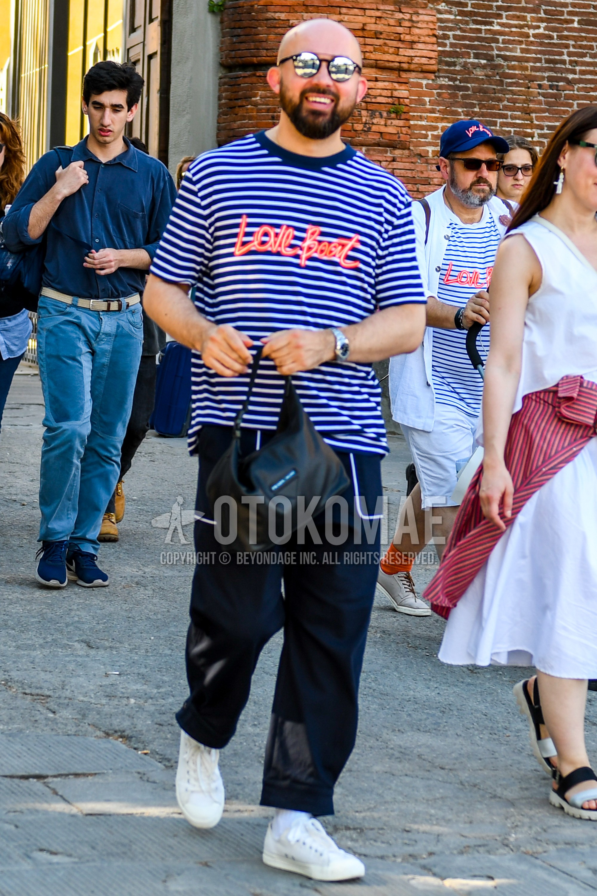 Men's summer outfit with plain sunglasses, white navy horizontal stripes t-shirt, navy plain beltless pants, white plain socks, white low-cut sneakers.