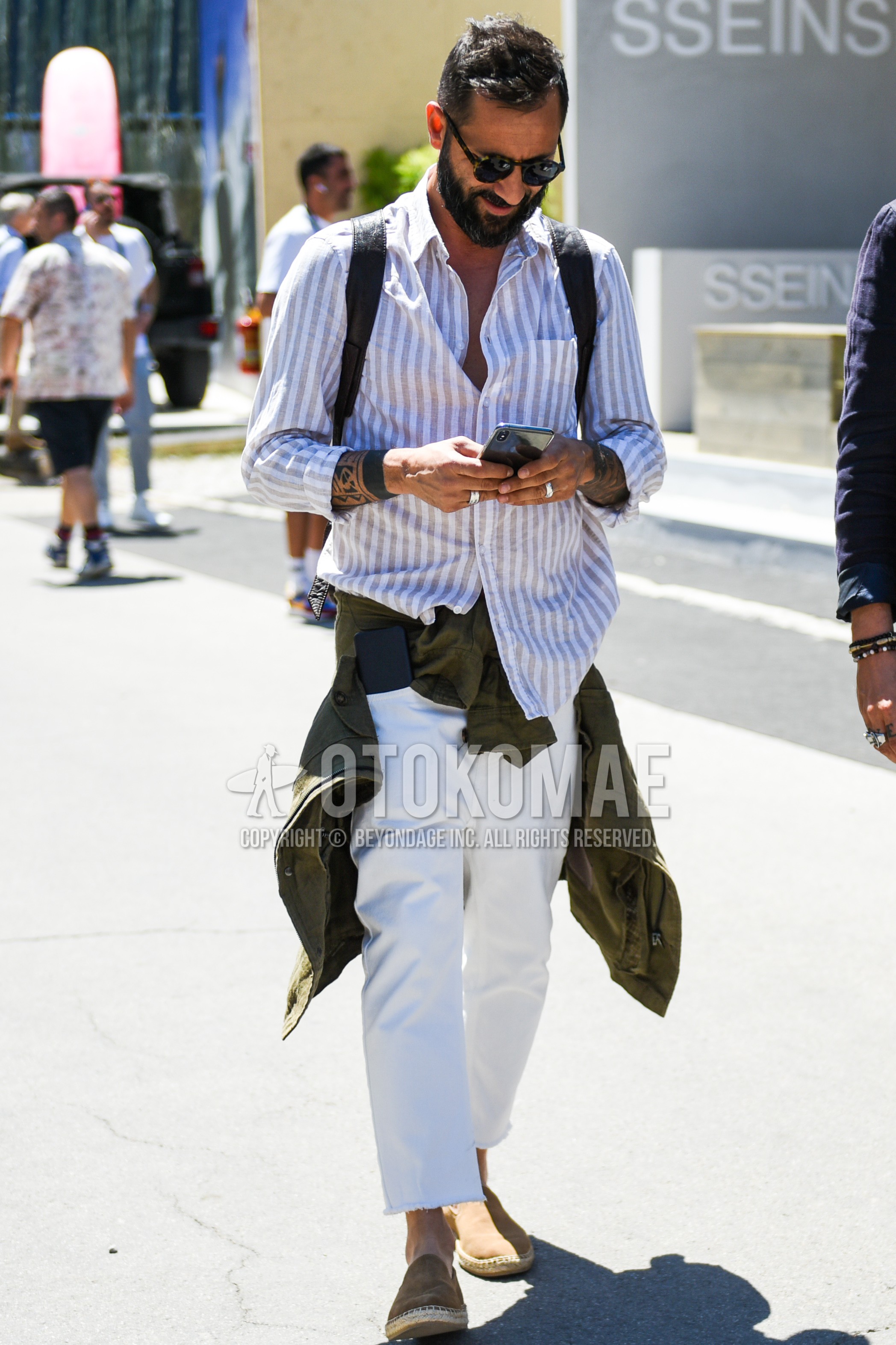 Men's spring summer outfit with beige tortoiseshell sunglasses, white beige stripes shirt, white plain cotton pants, beige plain espadrille.