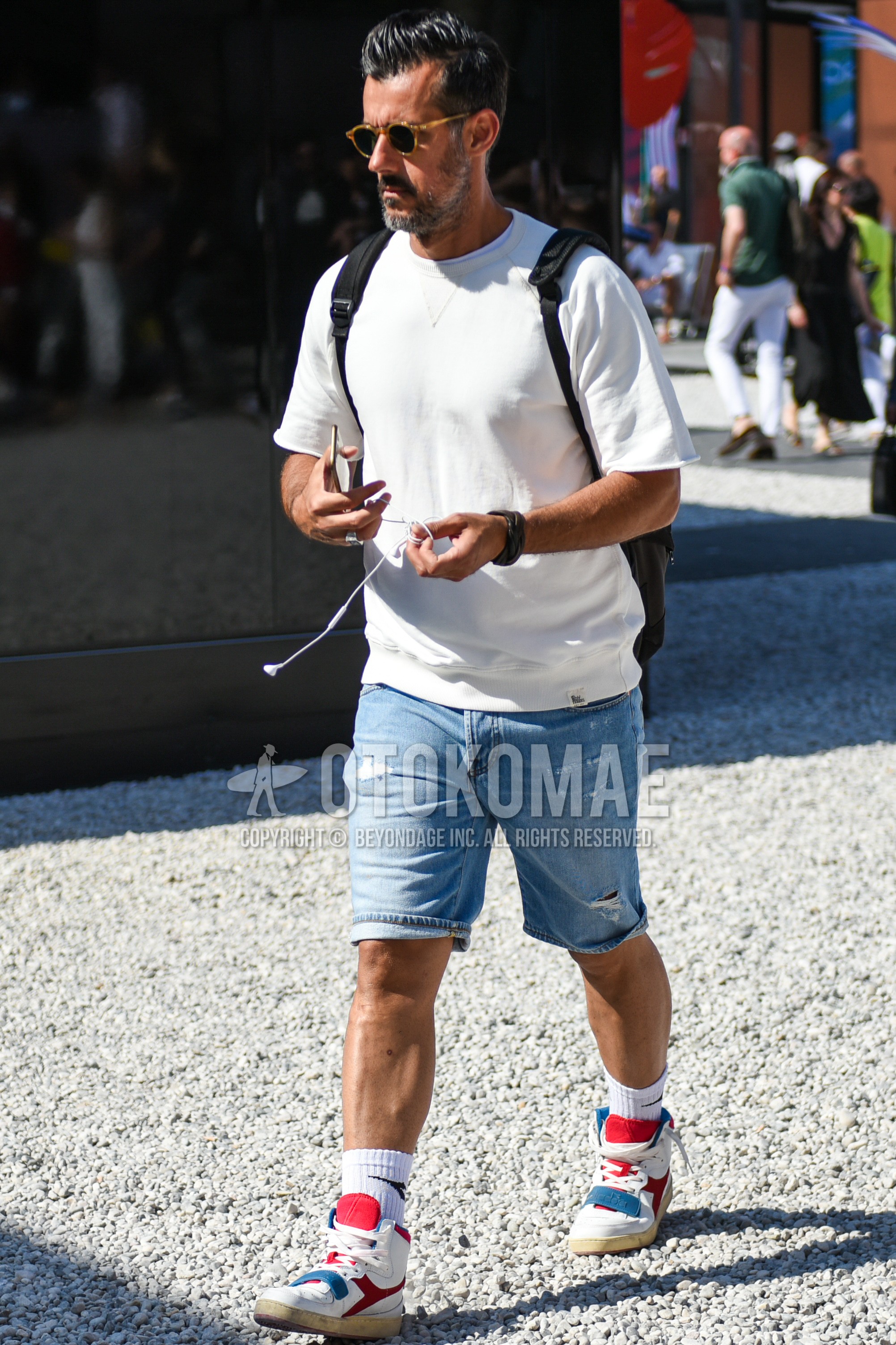Men's summer outfit with brown tortoiseshell sunglasses, white plain t-shirt, light blue plain denim/jeans, white deca logo socks, white low-cut sneakers.