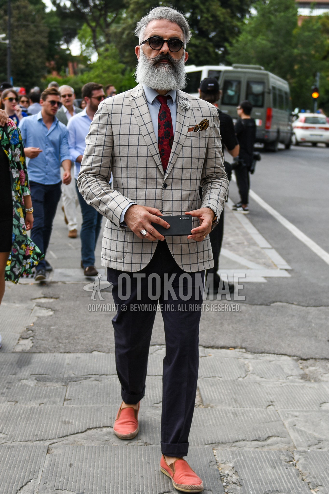 Men's spring summer autumn outfit with black plain sunglasses, beige check tailored jacket, gray plain shirt, gray plain slacks, orange red plain espadrille, red botanical necktie.