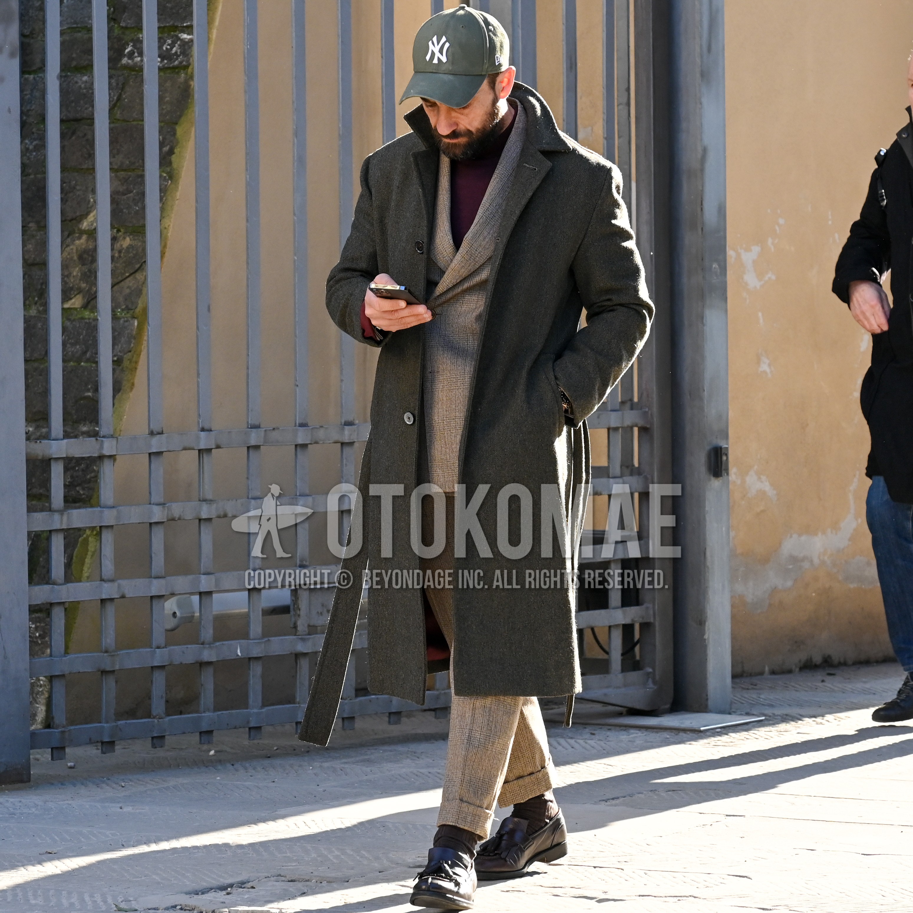 Men's autumn winter outfit with gray one point baseball cap, dark gray plain belted coat, brown plain sweater, brown plain socks, black tassel loafers leather shoes, beige check suit.