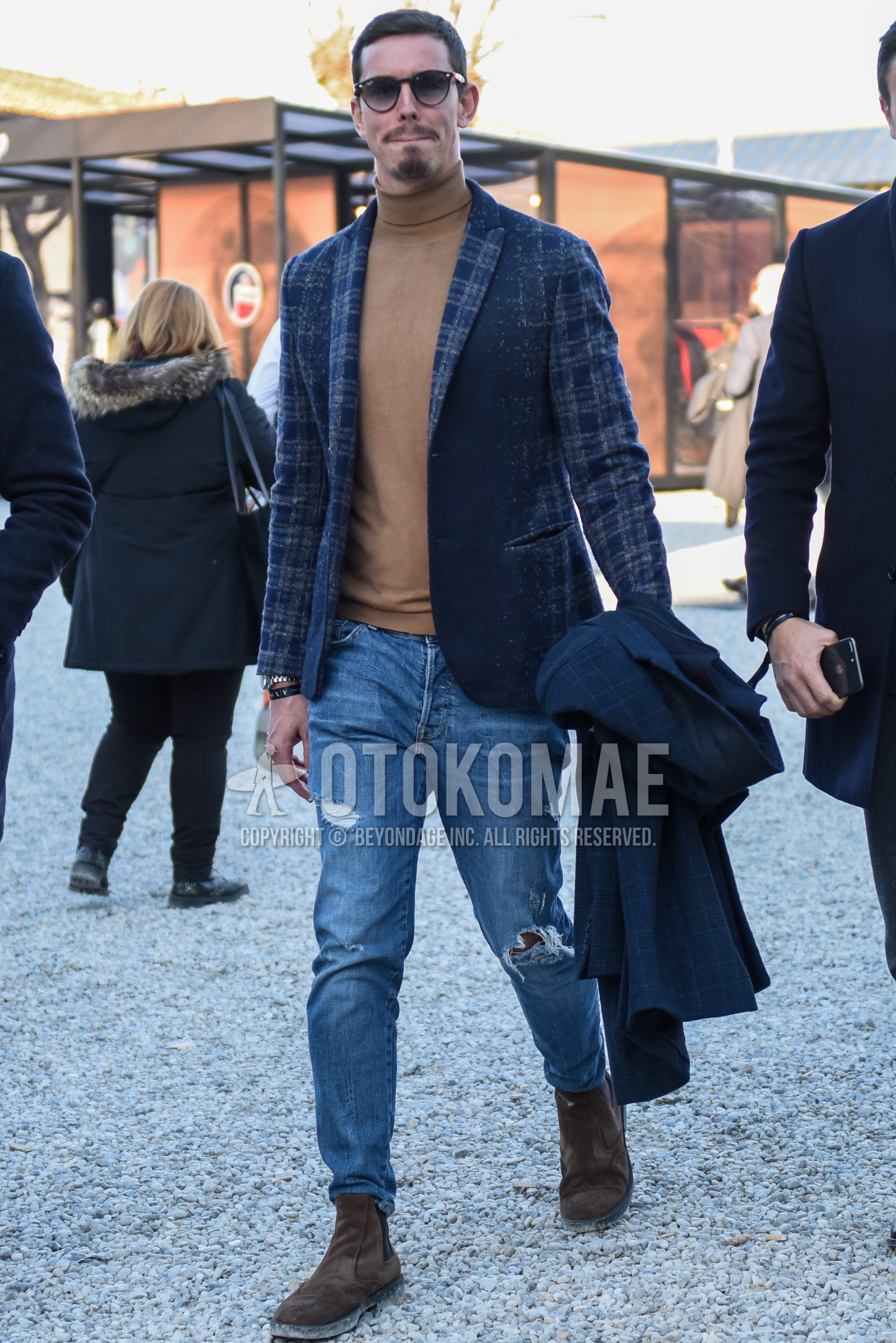 Men's spring autumn outfit with brown tortoiseshell sunglasses, gray check tailored jacket, beige plain turtleneck knit, blue plain damaged jeans, brown side-gore boots.