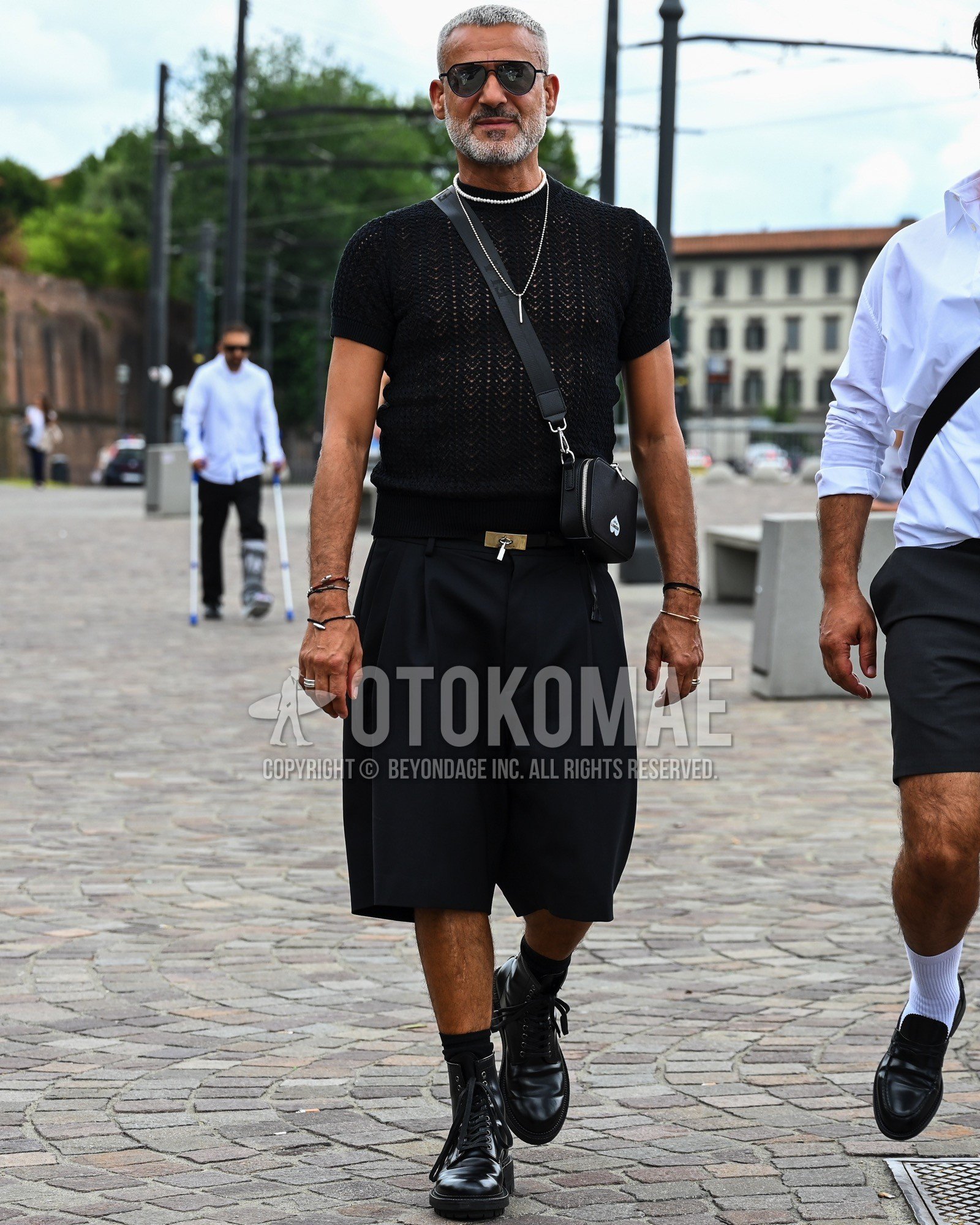 Men's spring summer outfit with black plain sunglasses, black plain t-shirt, black plain leather belt, black plain short pants, black plain socks, black  boots, black plain shoulder bag.