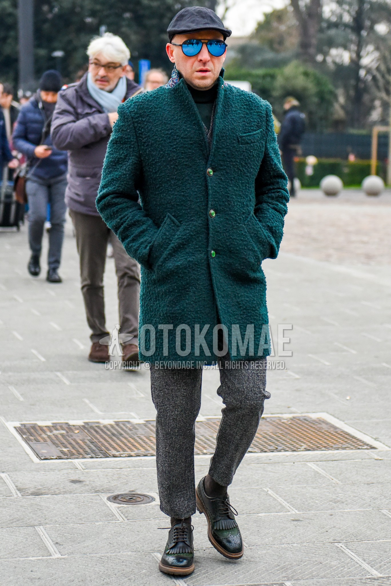 Men's winter outfit with black plain cap, plain sunglasses, green plain chester coat, gray plain ankle pants, brown plain socks, green suede shoes leather shoes.