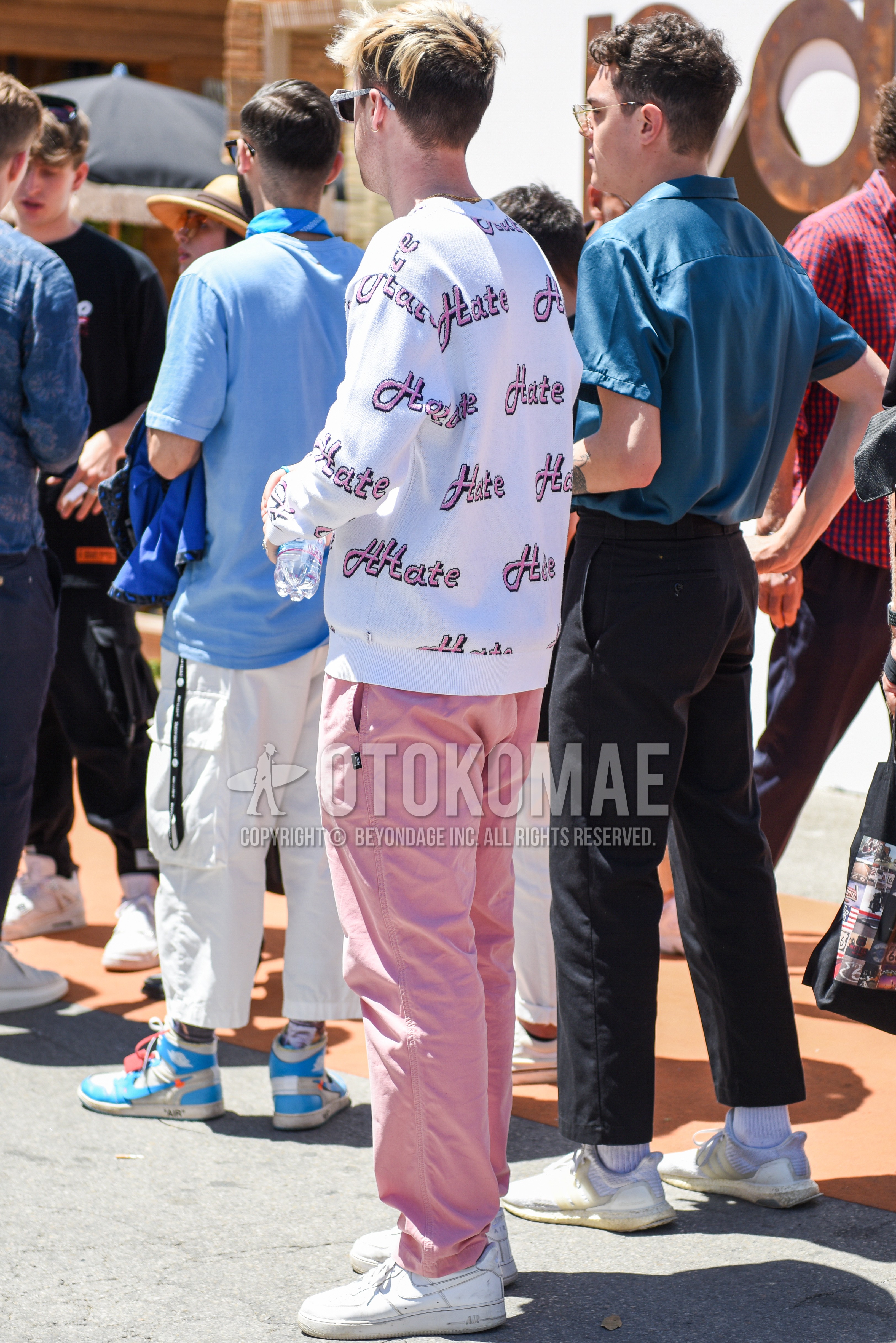 Men's spring autumn outfit with white graphic sweater, pink plain cotton pants, white low-cut sneakers.