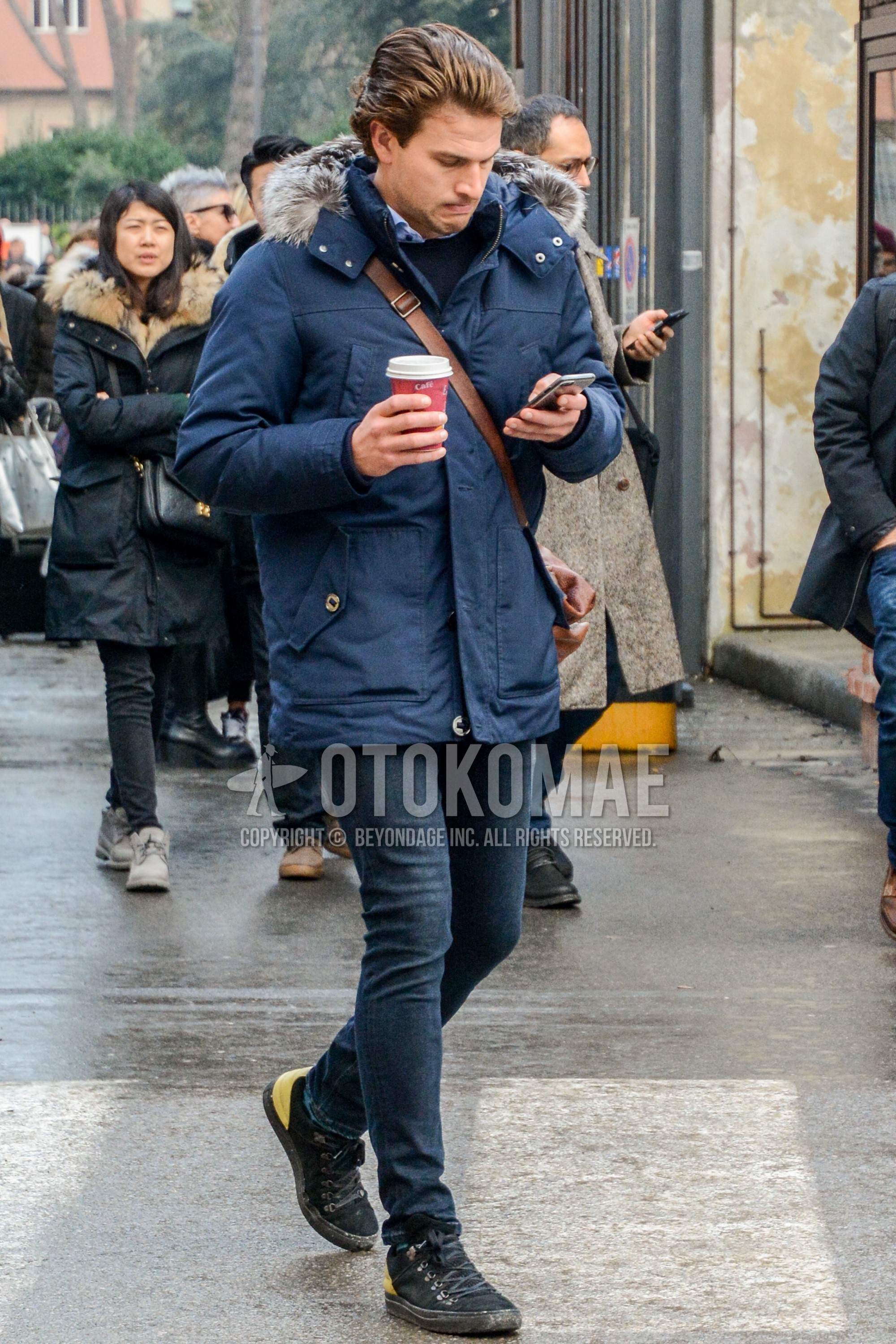 Men's winter outfit with navy plain down jacket, navy plain sweater, navy plain denim/jeans, black high-cut sneakers.