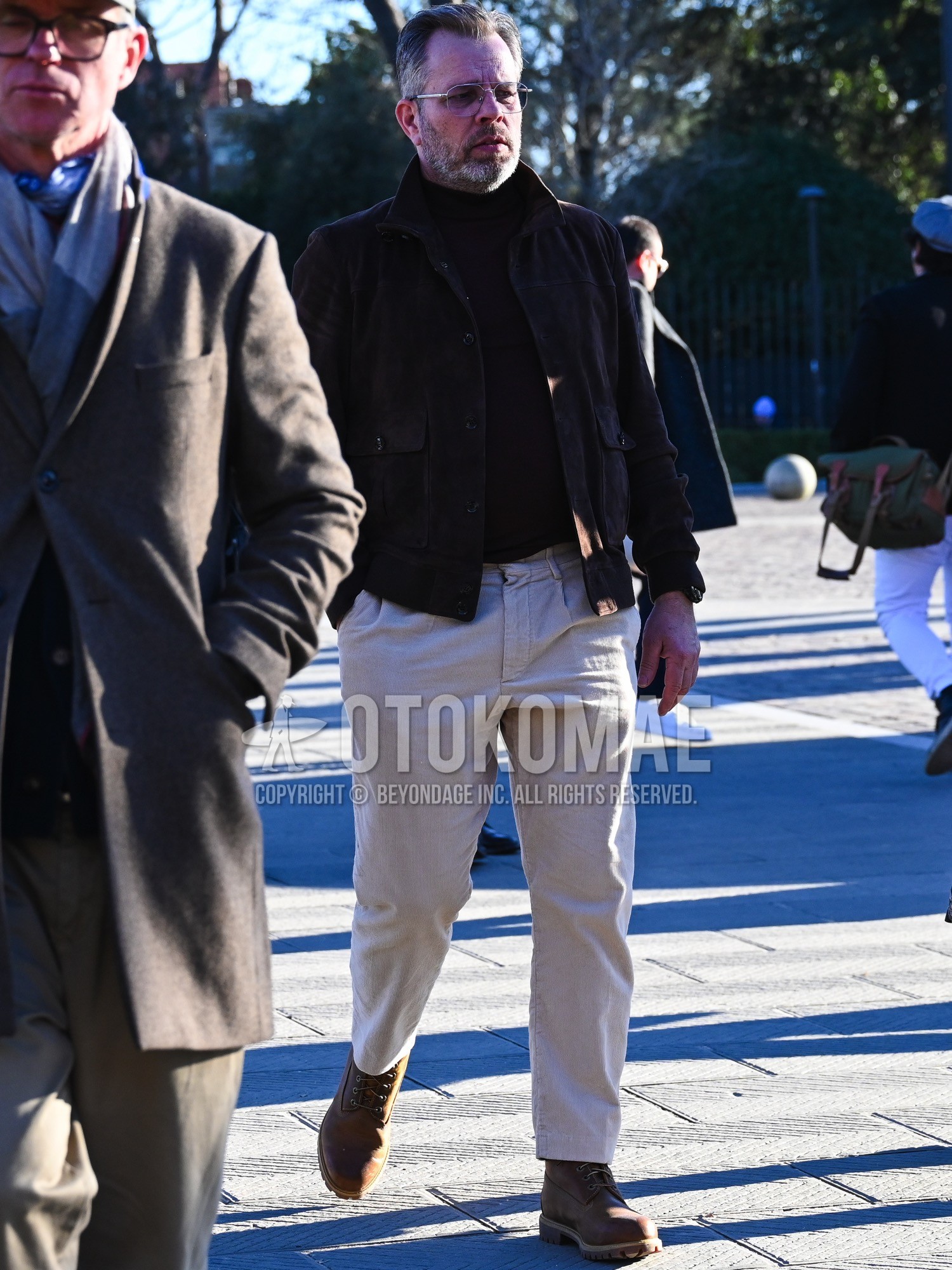 Men's autumn winter outfit with clear plain sunglasses, brown plain leather jacket, brown plain turtleneck knit, beige plain winter pants (corduroy,velour), brown work boots.