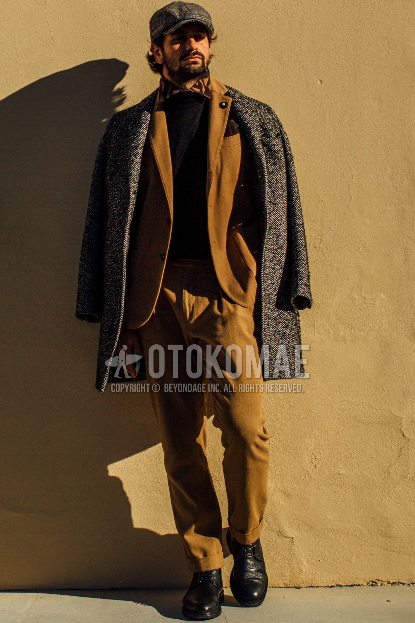 Men's spring winter outfit with gray check hunting cap, gray herringbone chester coat, black plain sweater, yellow orange tops/innerwear shirt, black plain toe leather shoes, beige plain suit.