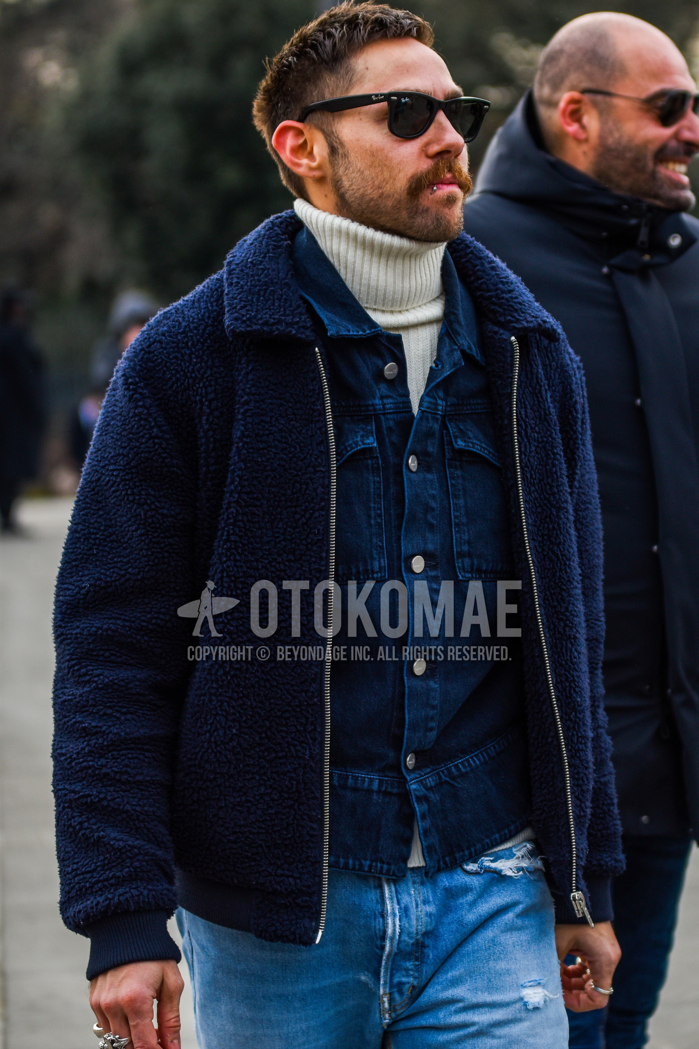 Men's autumn winter outfit with black plain sunglasses, navy plain fleece jacket, navy plain denim jacket, white plain turtleneck knit, blue plain damaged jeans.