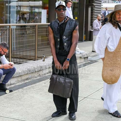 メッシュの白・黒ワンポイントのベースボールキャップ、シルバー無地のサングラス、黒ペイズリーのバンダナ/ネッカチーフ、レザーの黒無地のカジュアルベスト、黒無地のTシャツ、黒無地のスラックス、黒無地のコットンパンツ、黒無地のプリーツパンツ、黒無地のワイドパンツ、黒ローファーの革靴、レザーのブラウン無地のブリーフケース/ハンドバッグを合わせた春夏のメンズコーデ・着こなし。