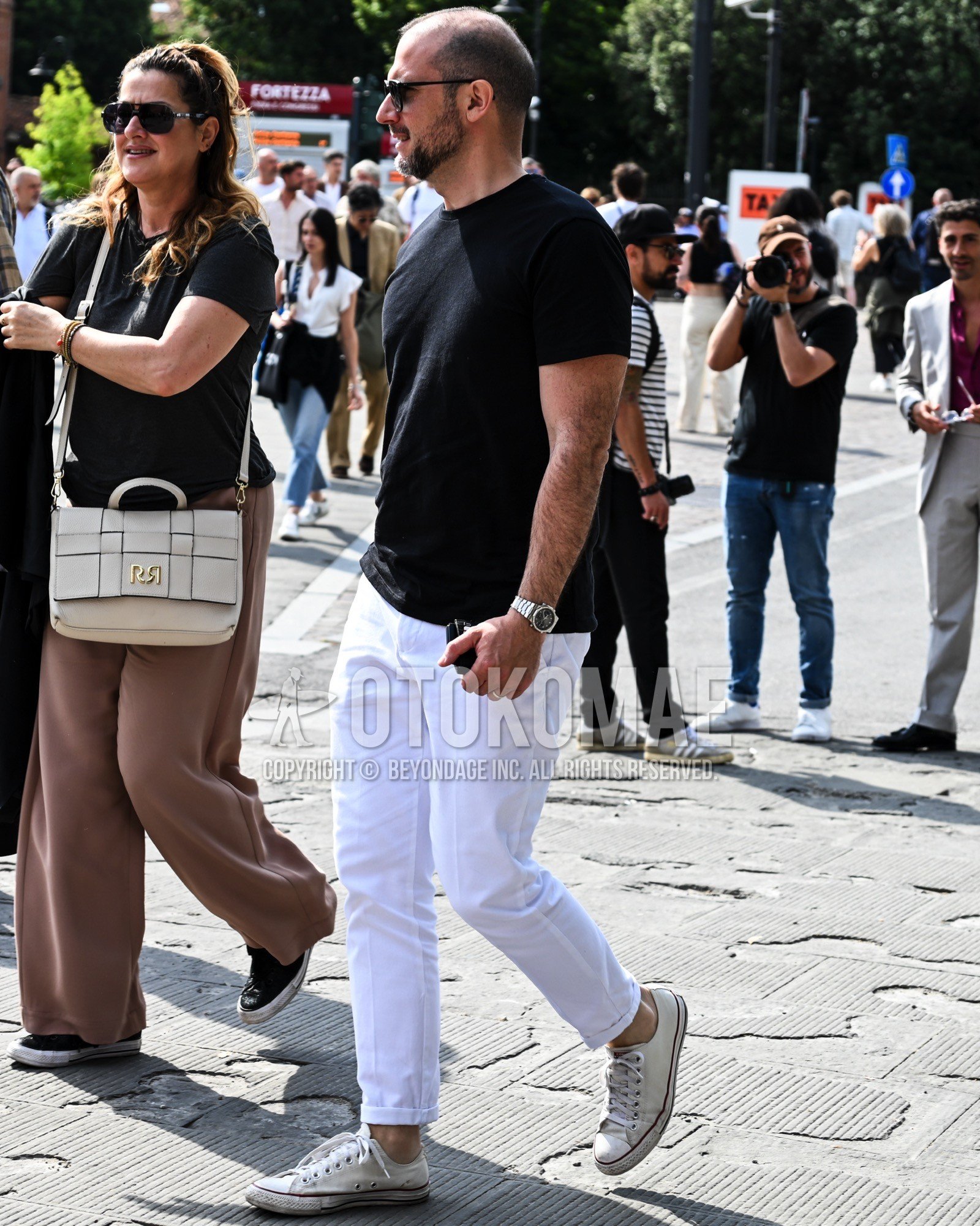 Men's spring summer outfit with black plain t-shirt, white plain denim/jeans, white low-cut sneakers.