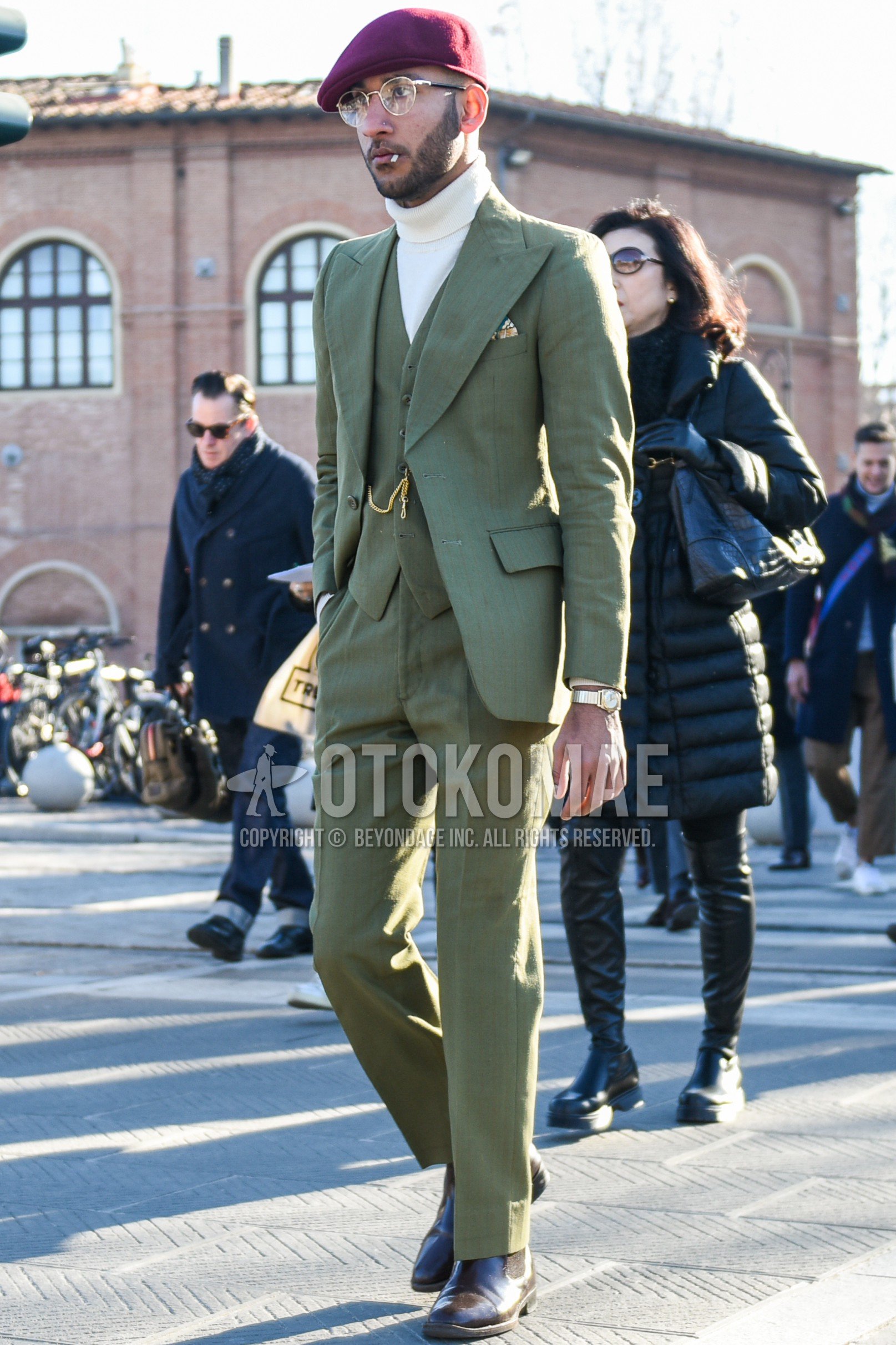 Men's autumn winter outfit with red plain hunting cap, silver plain glasses, white plain turtleneck knit, brown side-gore boots, olive green plain three-piece suit.