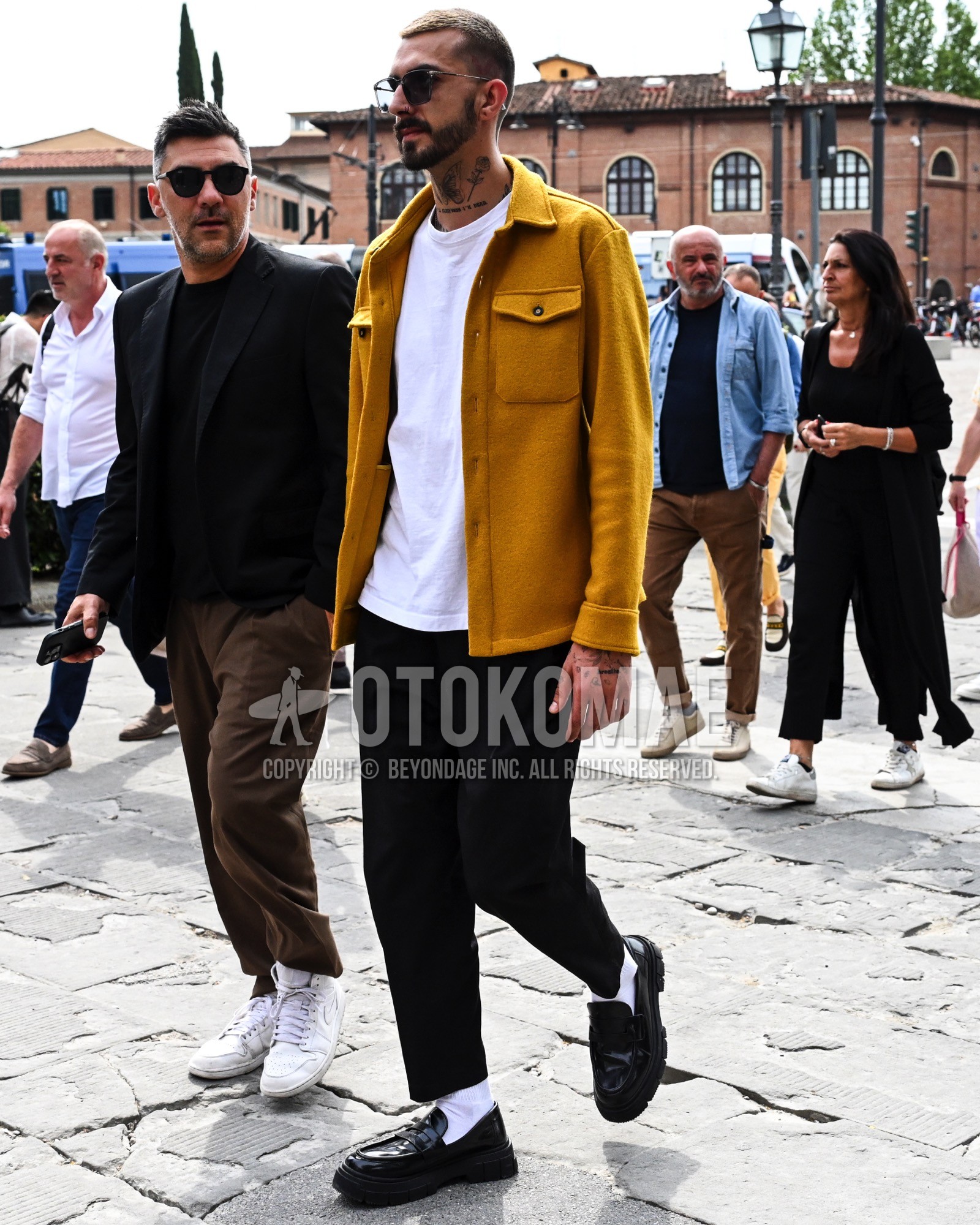 Men's spring summer autumn outfit with black plain sunglasses, yellow plain coverall, white plain t-shirt, black plain chinos, white plain socks, black coin loafers leather shoes.