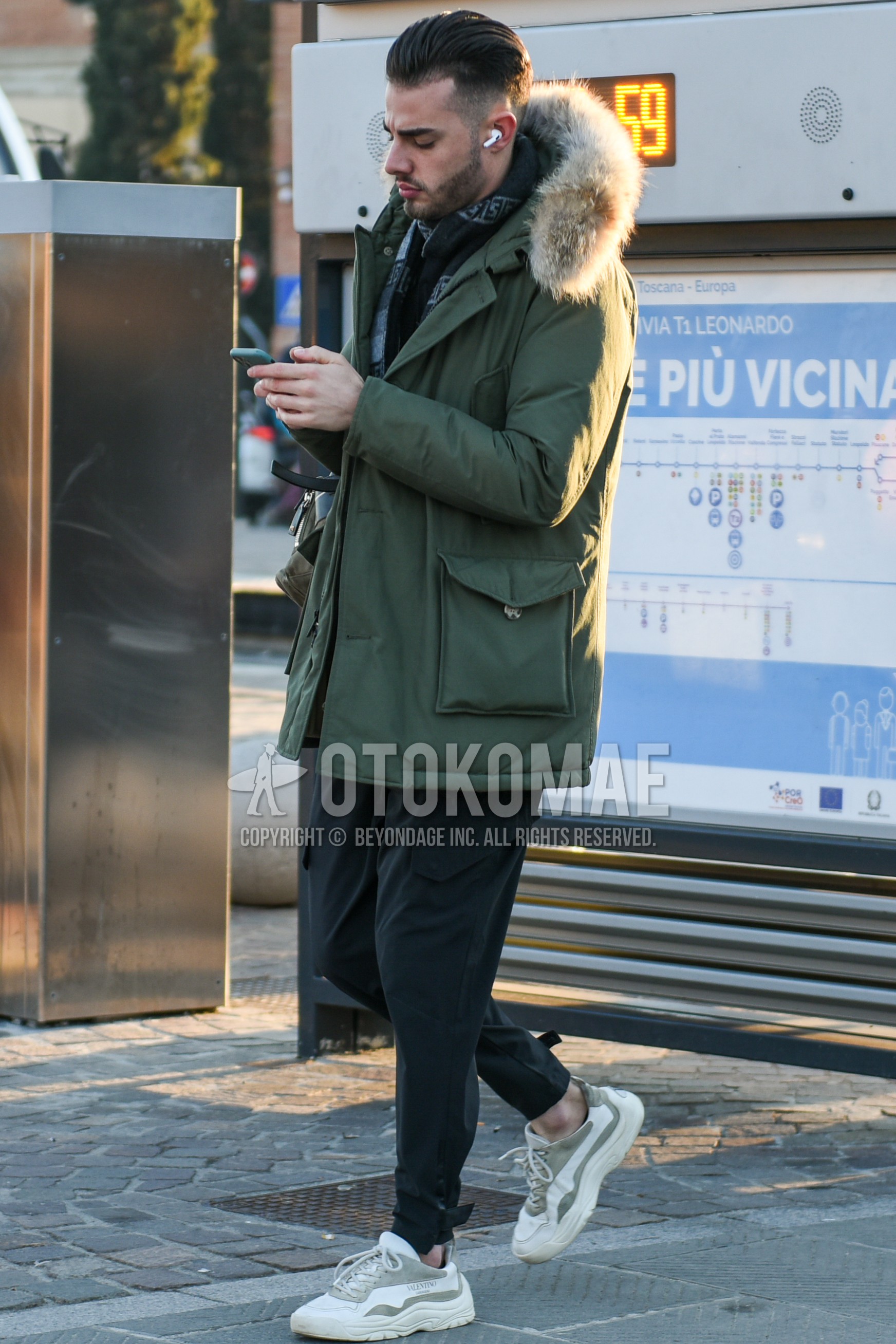 Men's winter outfit with dark gray scarf scarf, olive green plain hooded coat, olive green plain down jacket, dark gray plain slacks, dark gray plain cargo pants, white low-cut sneakers.