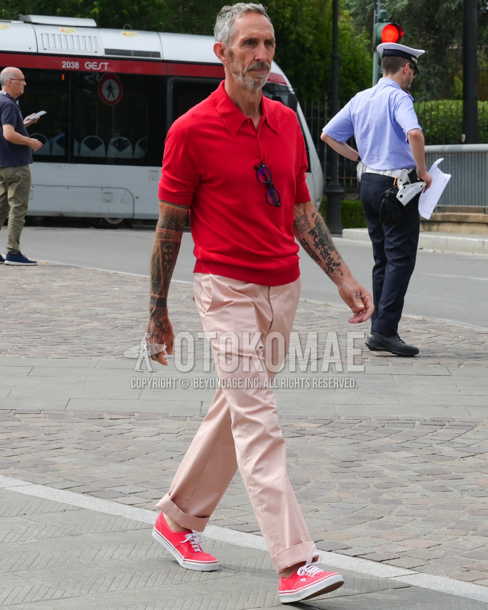 Men's spring summer outfit with red plain polo shirt, pink plain slacks, red low-cut sneakers.