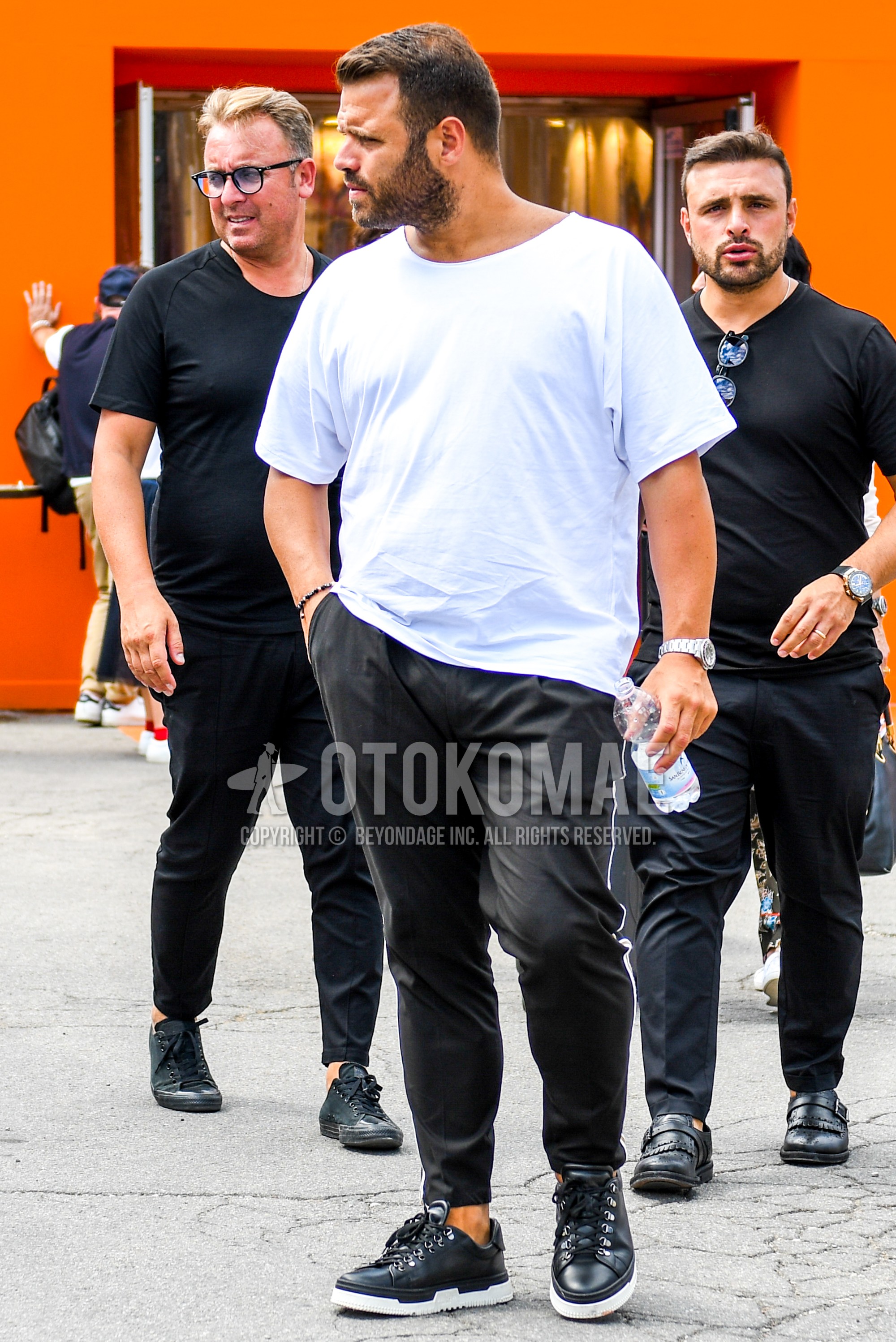 Men's summer outfit with white plain t-shirt, black plain beltless pants, black low-cut sneakers.
