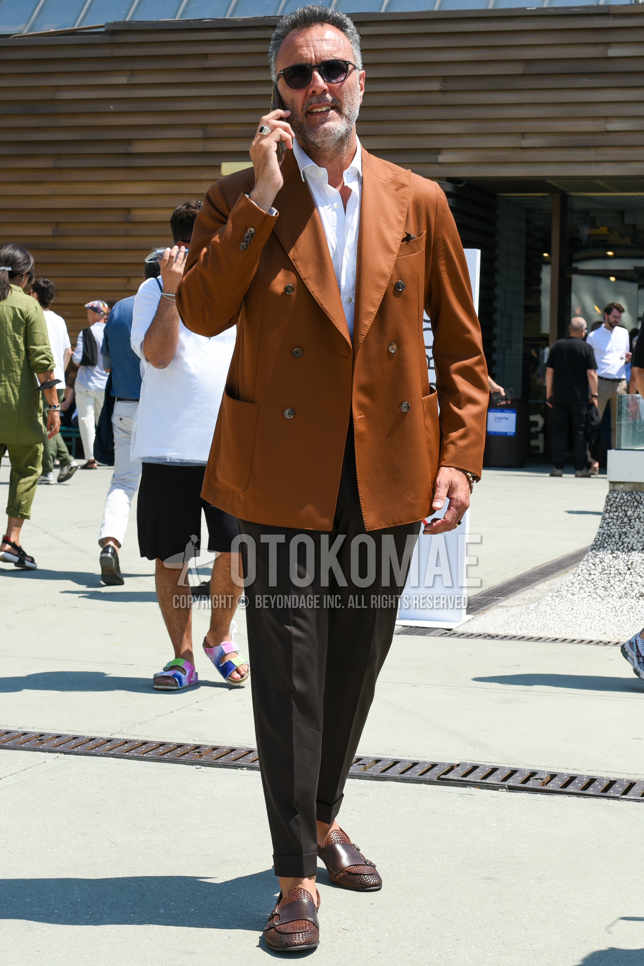Men's spring summer outfit with black plain sunglasses, orange plain tailored jacket, white plain shirt, brown plain slacks, brown  loafers leather shoes.