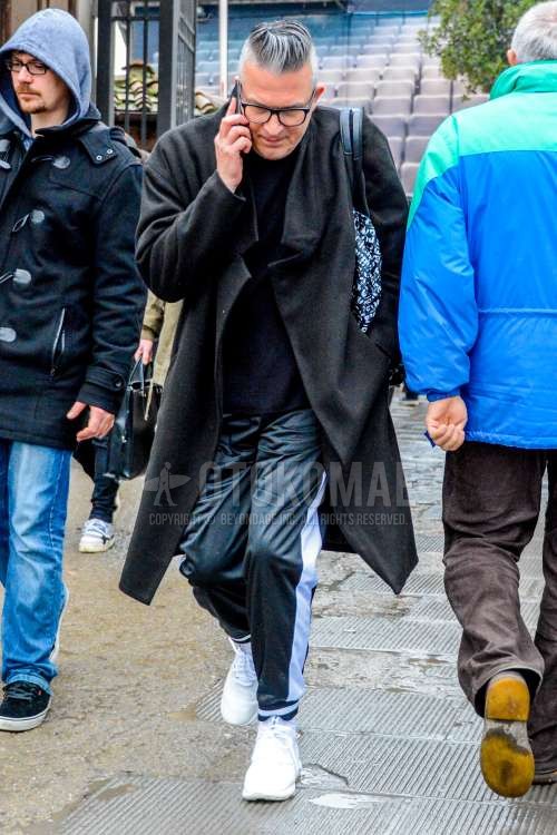 無地のメガネ、ダークグレー無地のアウター、黒無地のセーター、ダークグレー無地のサイドラインパンツ、白ローカットのスニーカーを合わせた冬のメンズコーデ・着こなし。