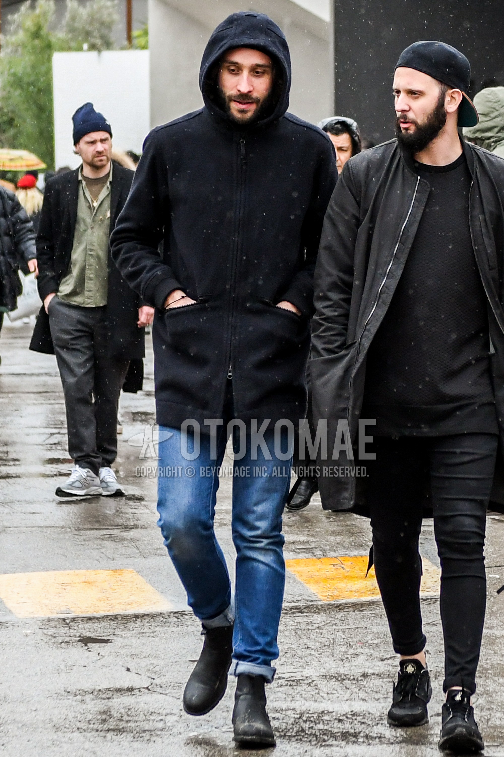 Men's autumn winter outfit with black plain hooded coat, blue plain denim/jeans, black side-gore boots.