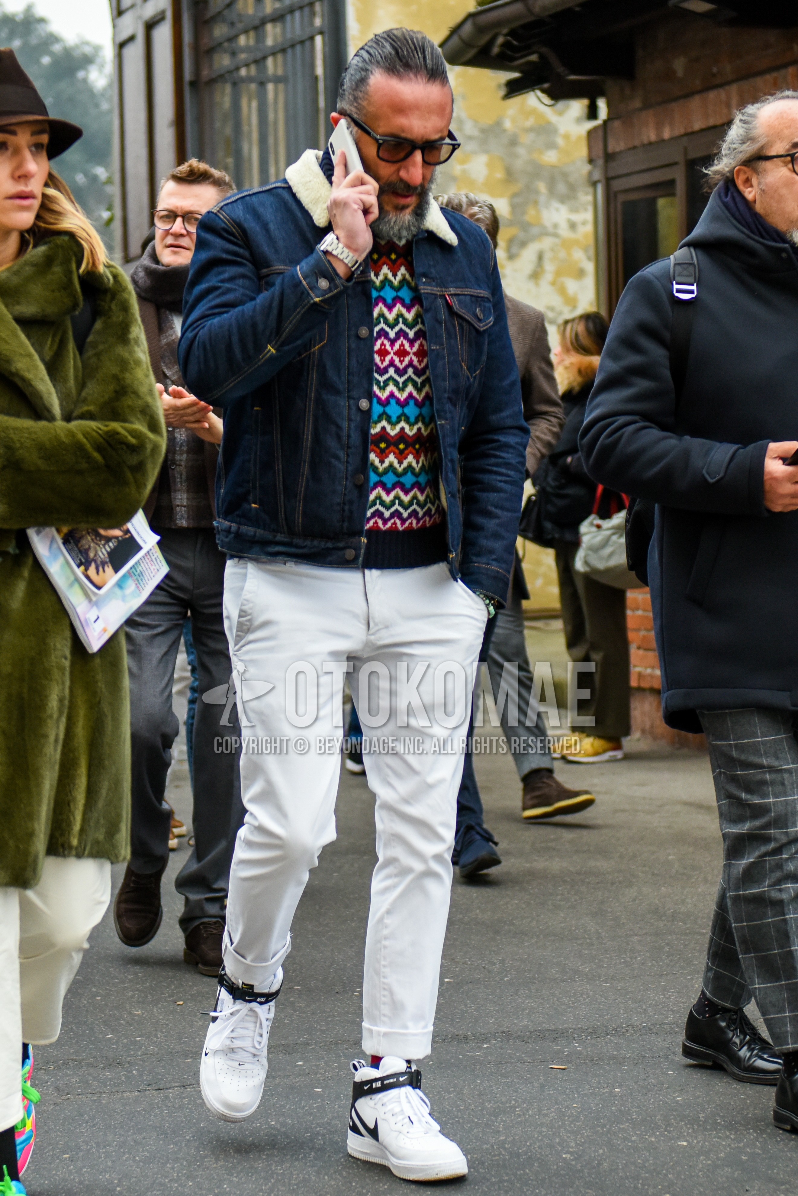 Men's winter outfit with plain sunglasses, navy plain denim jacket, multi-color tops/innerwear sweater, white plain chinos, white high-cut sneakers.