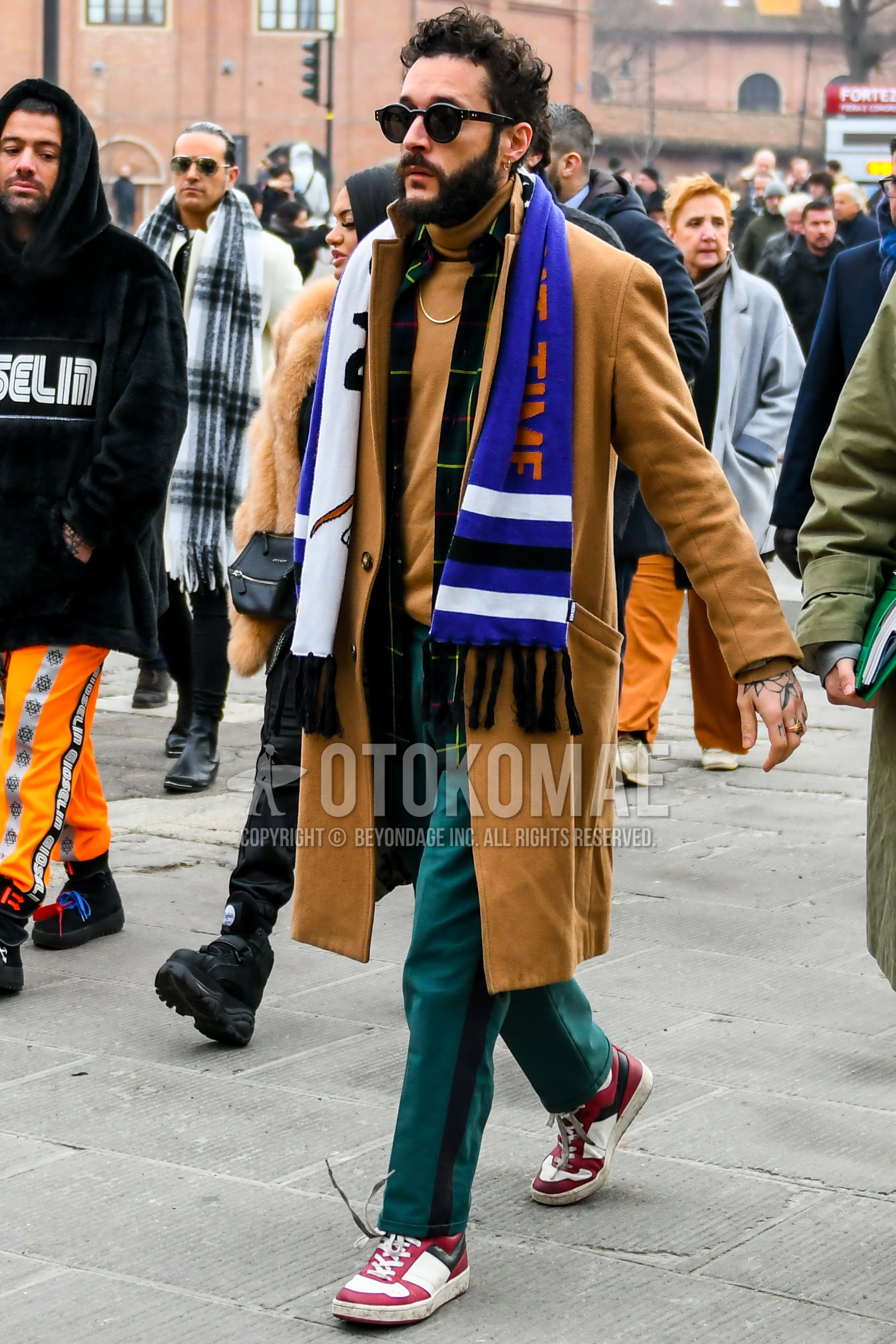 Men's autumn winter outfit with plain sunglasses, multi-color graphic scarf, beige plain chester coat, beige plain turtleneck knit, green plain sideline pants, white red high-cut sneakers.