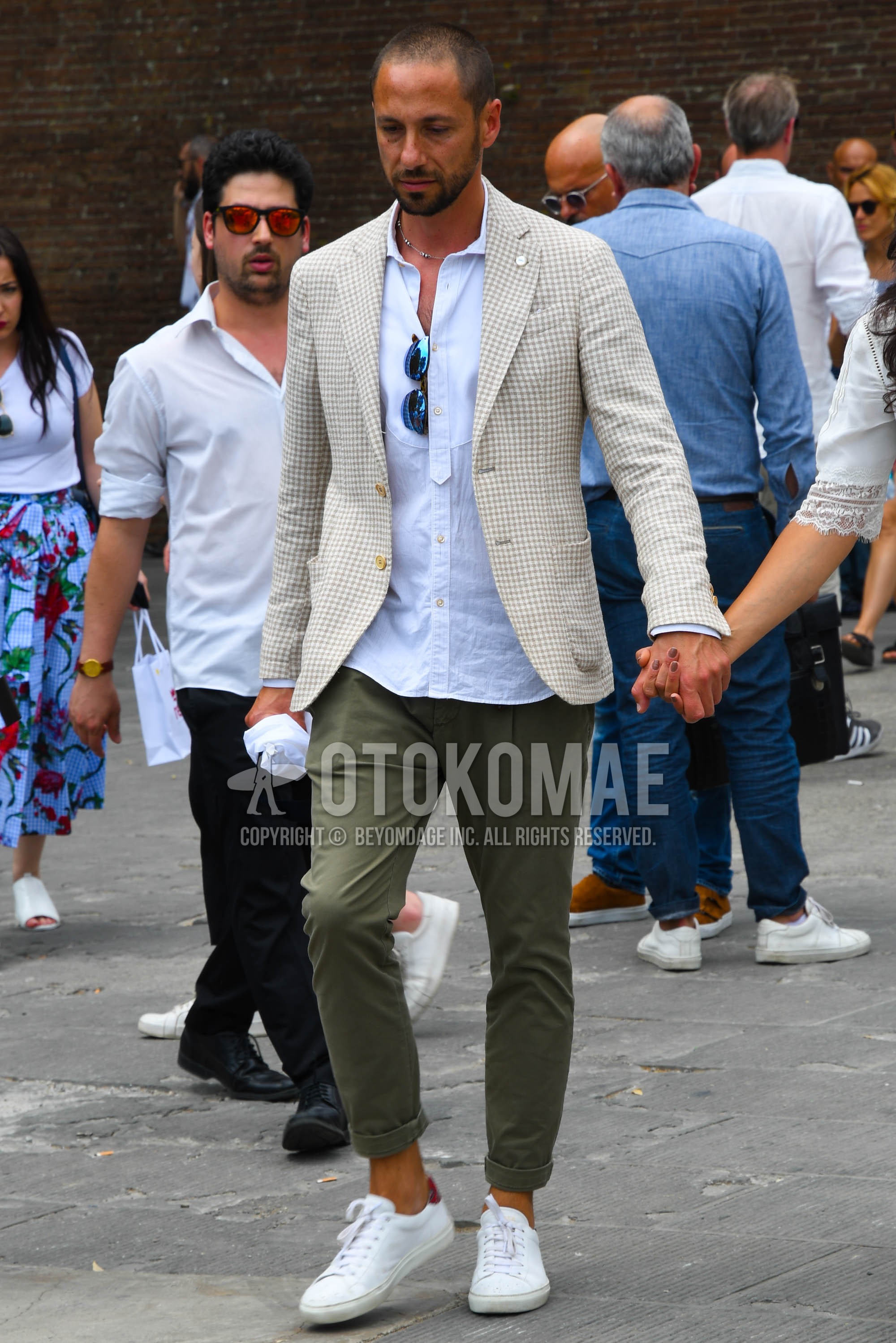 Men's spring summer autumn outfit with white beige check tailored jacket, white plain shirt, olive green plain chinos, white low-cut sneakers.