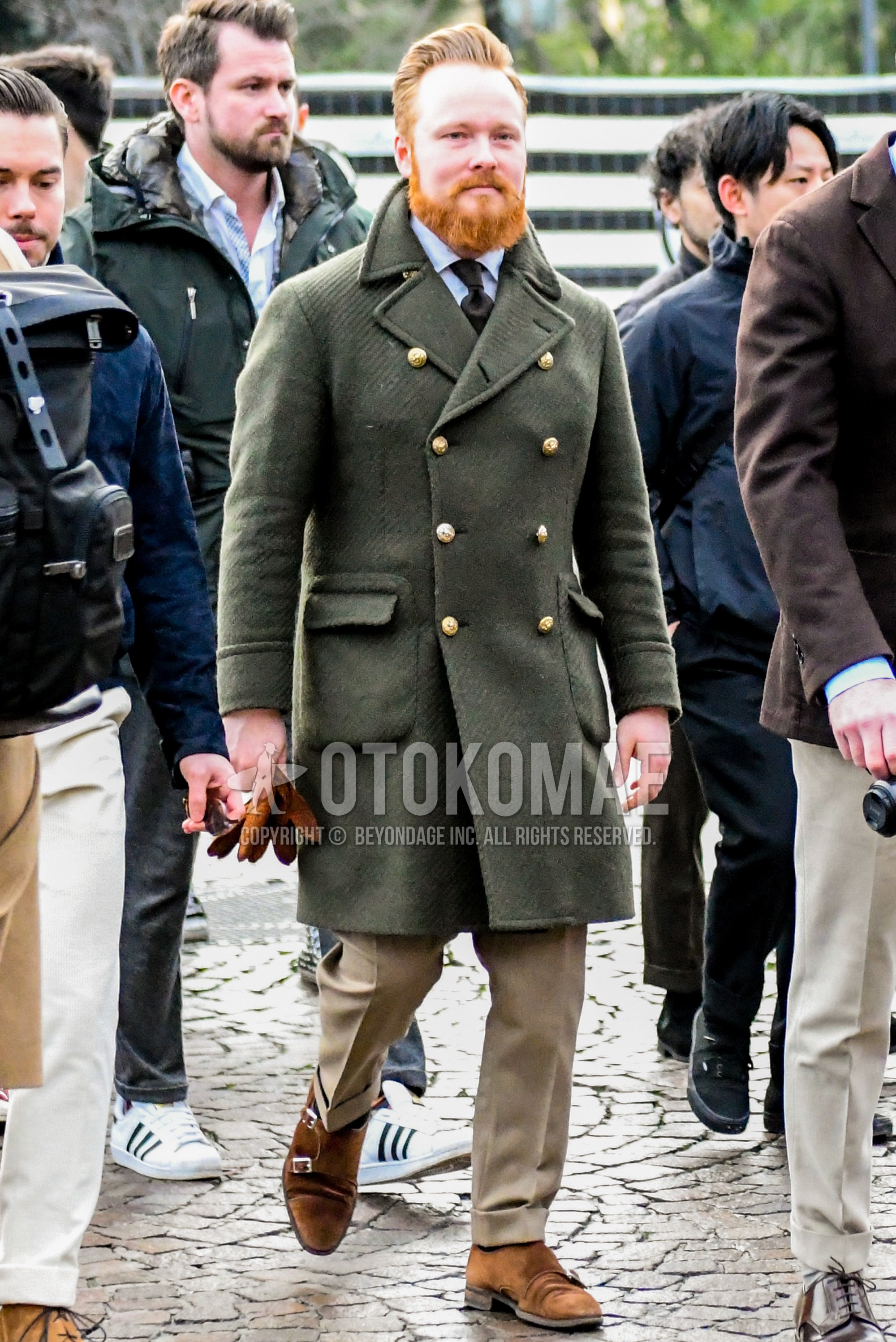 Men's winter outfit with olive green plain ulster coat, white plain shirt, beige plain slacks, brown monk shoes leather shoes, black plain necktie.