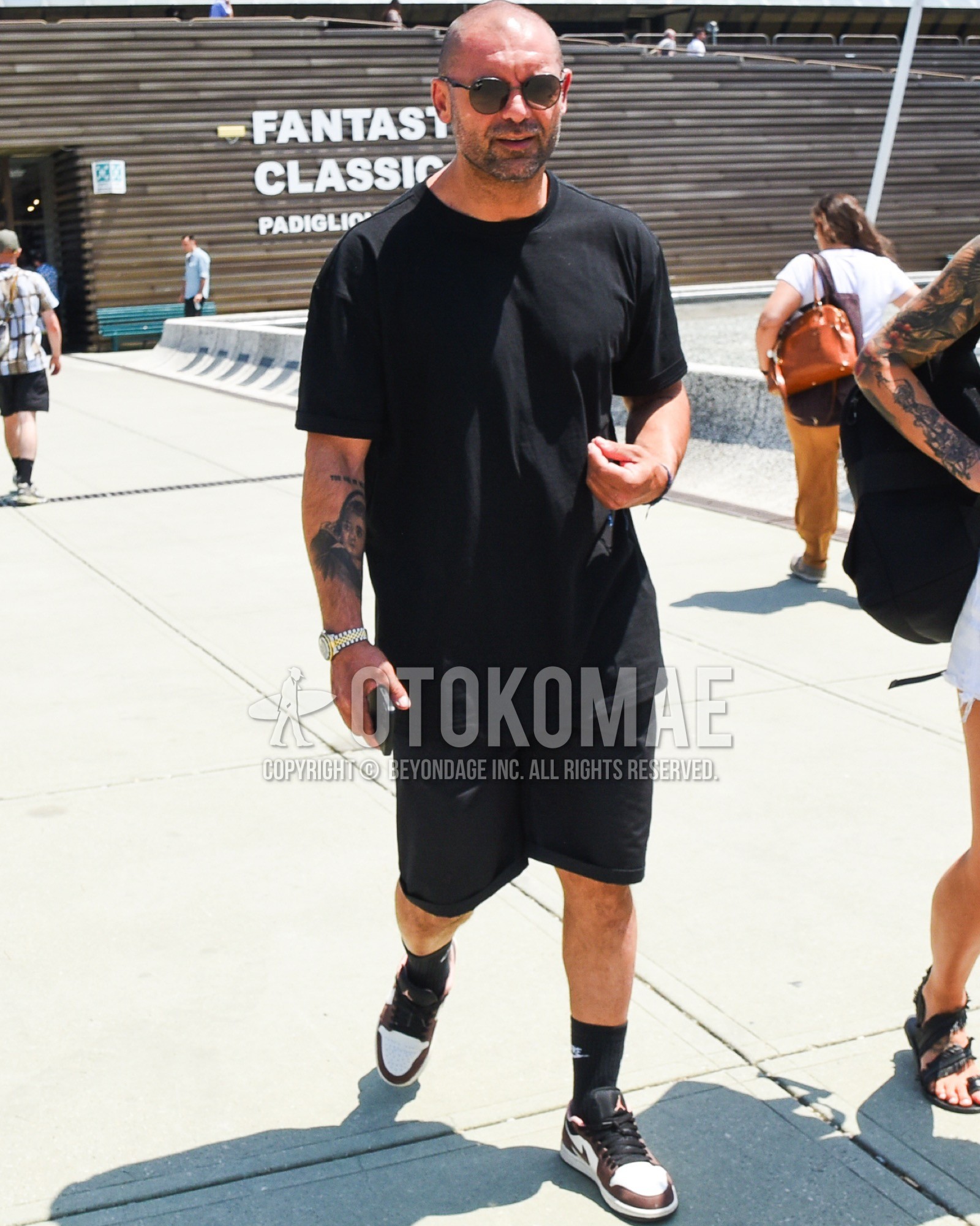 Men's spring summer outfit with black plain sunglasses, black plain t-shirt, black plain short pants, black one point socks, brown low-cut sneakers.
