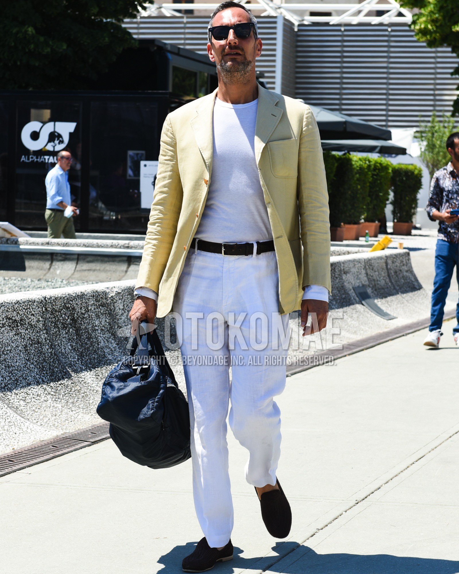 Men's spring summer outfit with black plain sunglasses, yellow plain tailored jacket, white plain t-shirt, black plain leather belt, white plain cotton pants, brown  loafers leather shoes, navy plain backpack.