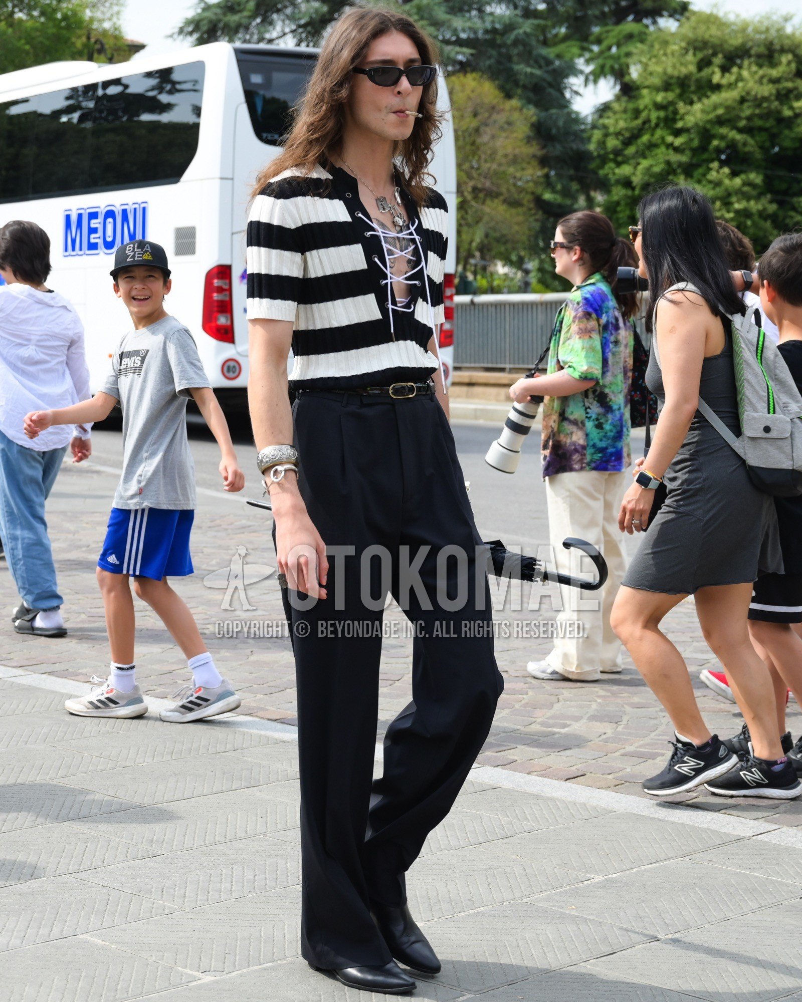 Men's spring summer outfit with black plain sunglasses, white black horizontal stripes t-shirt, black plain leather belt, black plain slacks, black side-gore boots.