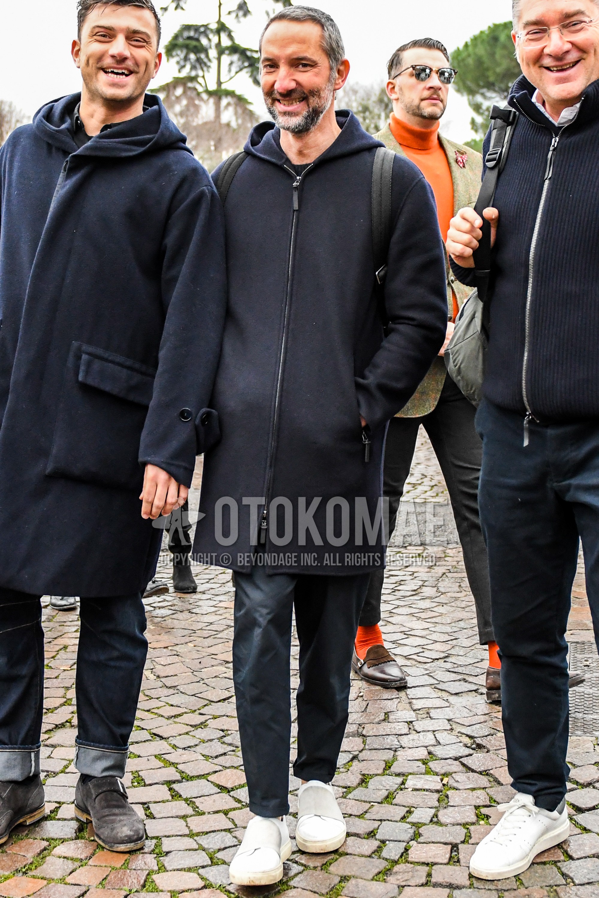 Men's autumn winter outfit with black plain hooded coat, gray plain slacks, white low-cut sneakers.