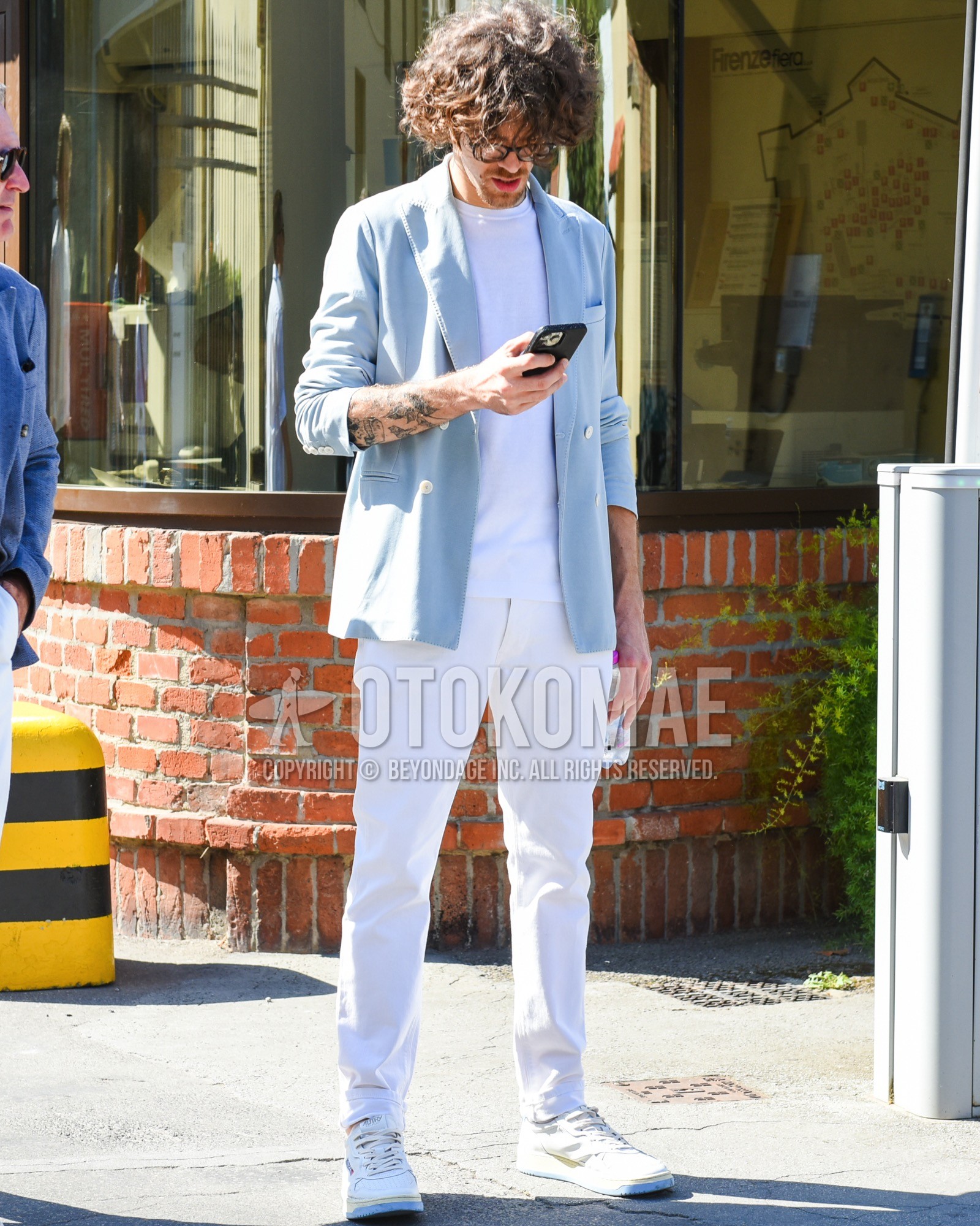 Men's spring summer outfit with brown graphic glasses, light blue plain tailored jacket, white plain t-shirt, white plain cotton pants, white low-cut sneakers.