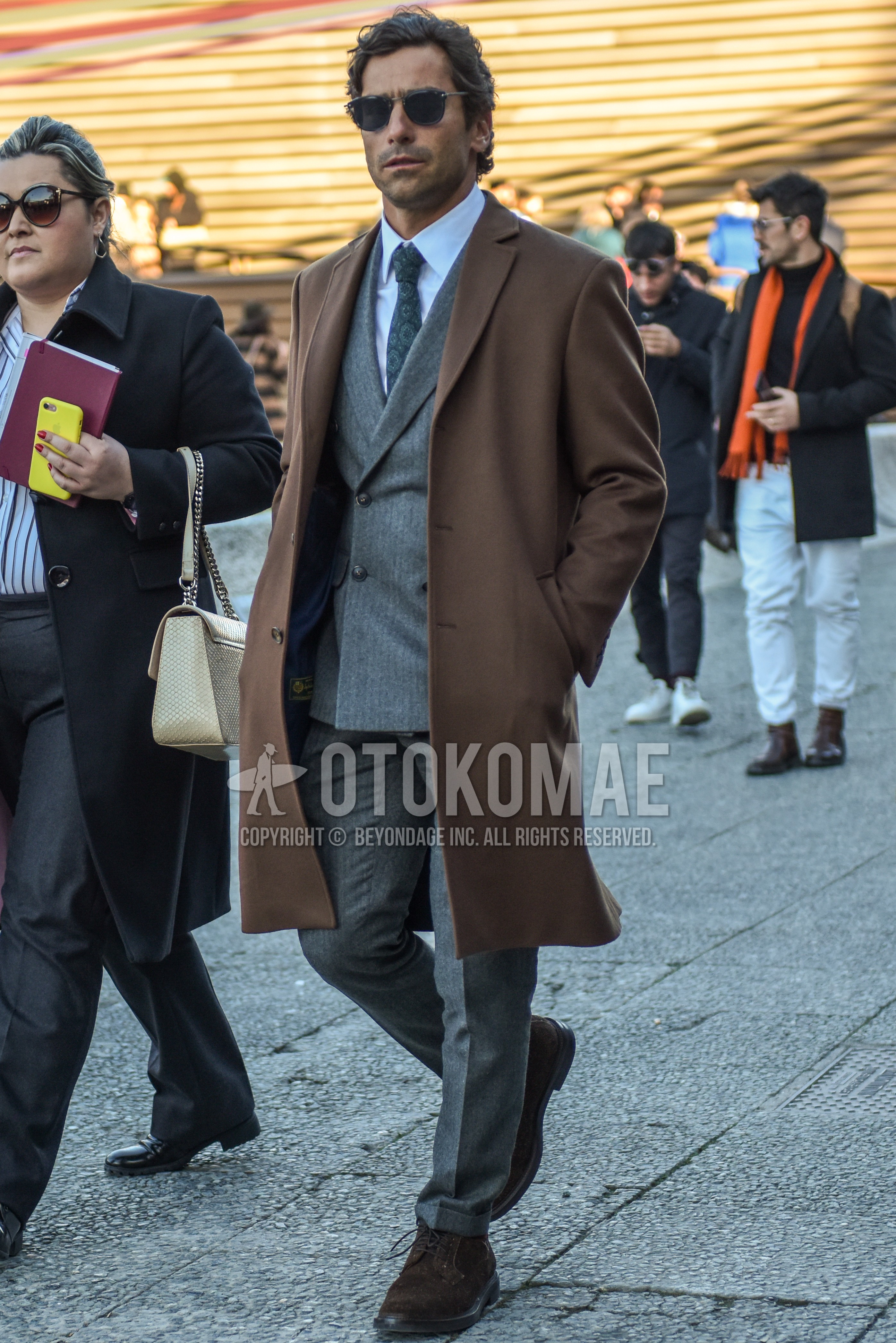 Men's autumn winter outfit with black plain sunglasses, beige plain chester coat, white plain shirt, brown  boots, gray plain suit, gray necktie necktie.