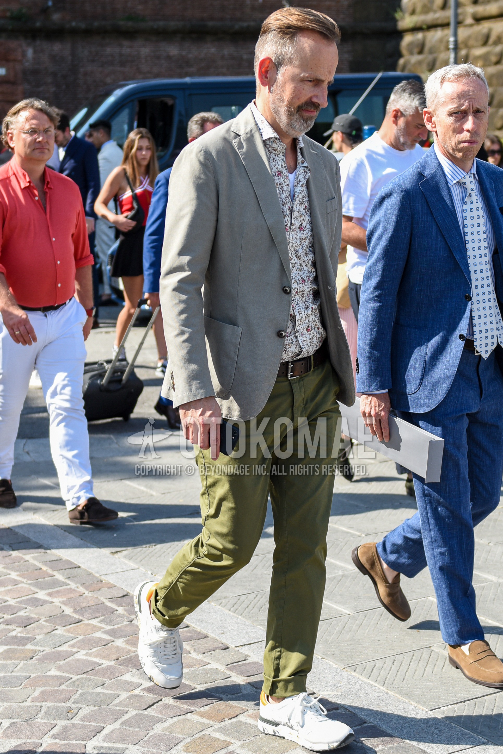 Men's spring summer autumn outfit with gray plain tailored jacket, white tops/innerwear shirt, brown plain leather belt, olive green plain chinos, white low-cut sneakers.
