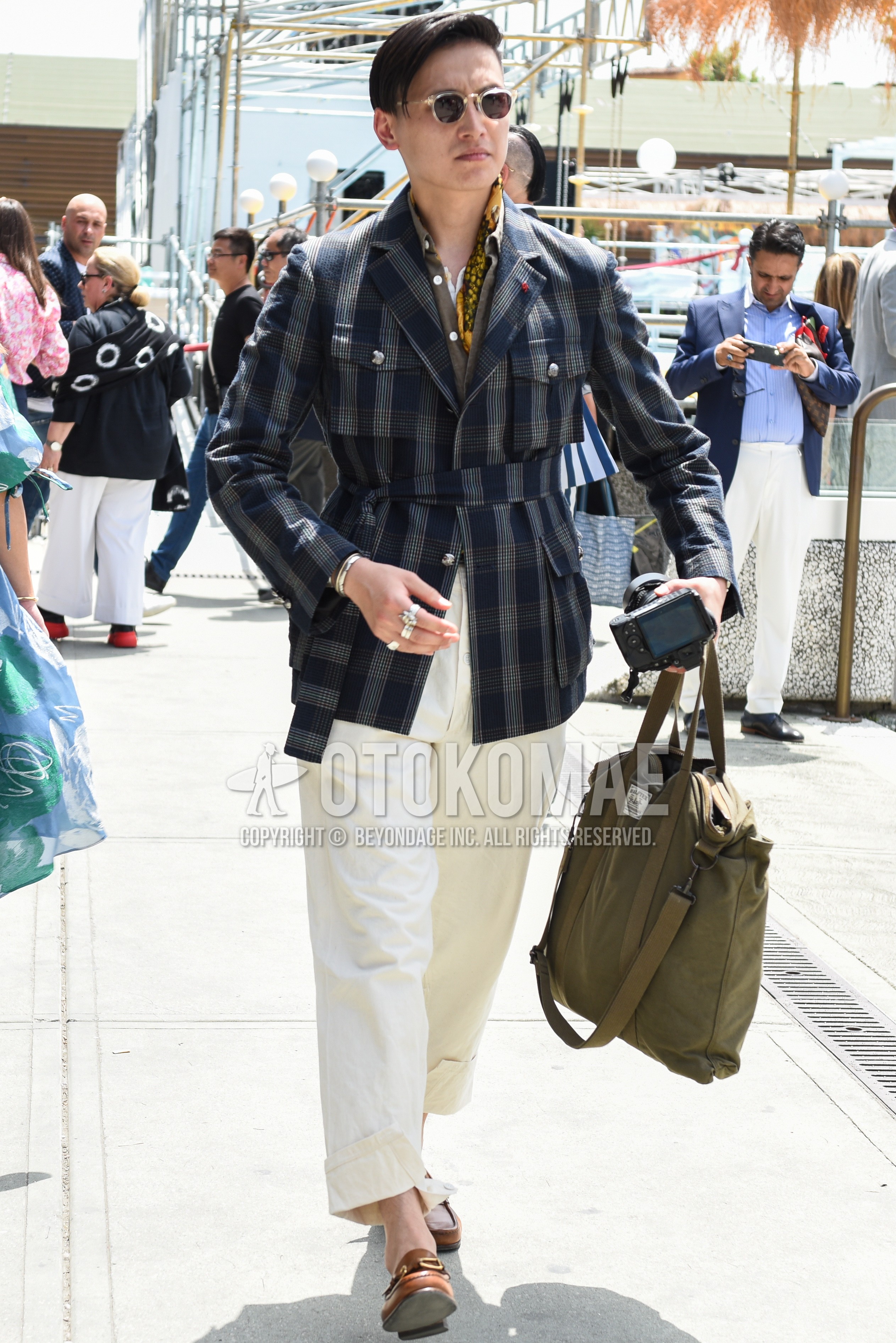 Men's spring autumn outfit with yellow scarf bandana/neckerchief, navy gray check safari jacket, white plain cotton pants, brown bit loafers leather shoes, olive green plain briefcase/handbag.
