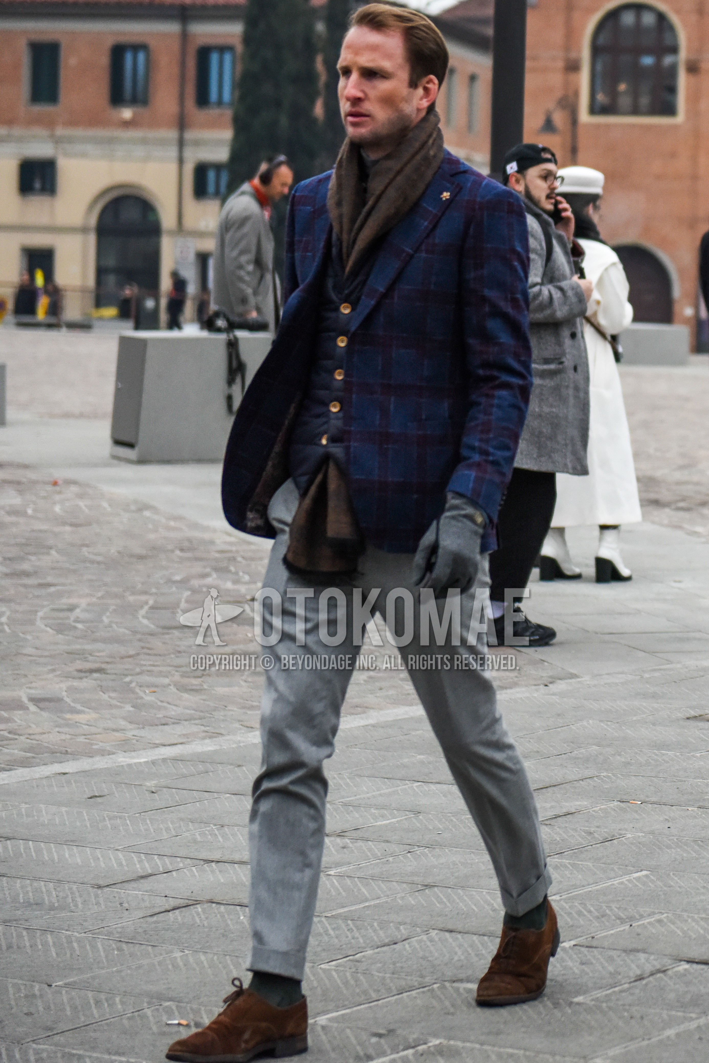 Men's autumn outfit with brown scarf scarf, navy check tailored jacket, navy check gilet, gray plain slacks, gray plain socks, brown suede shoes leather shoes.