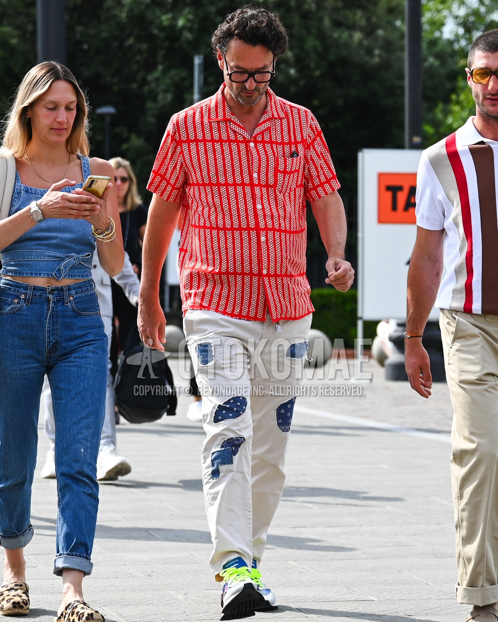 Men's spring summer outfit with orange plain sunglasses, red check shirt, white plain damaged jeans, white low-cut sneakers.