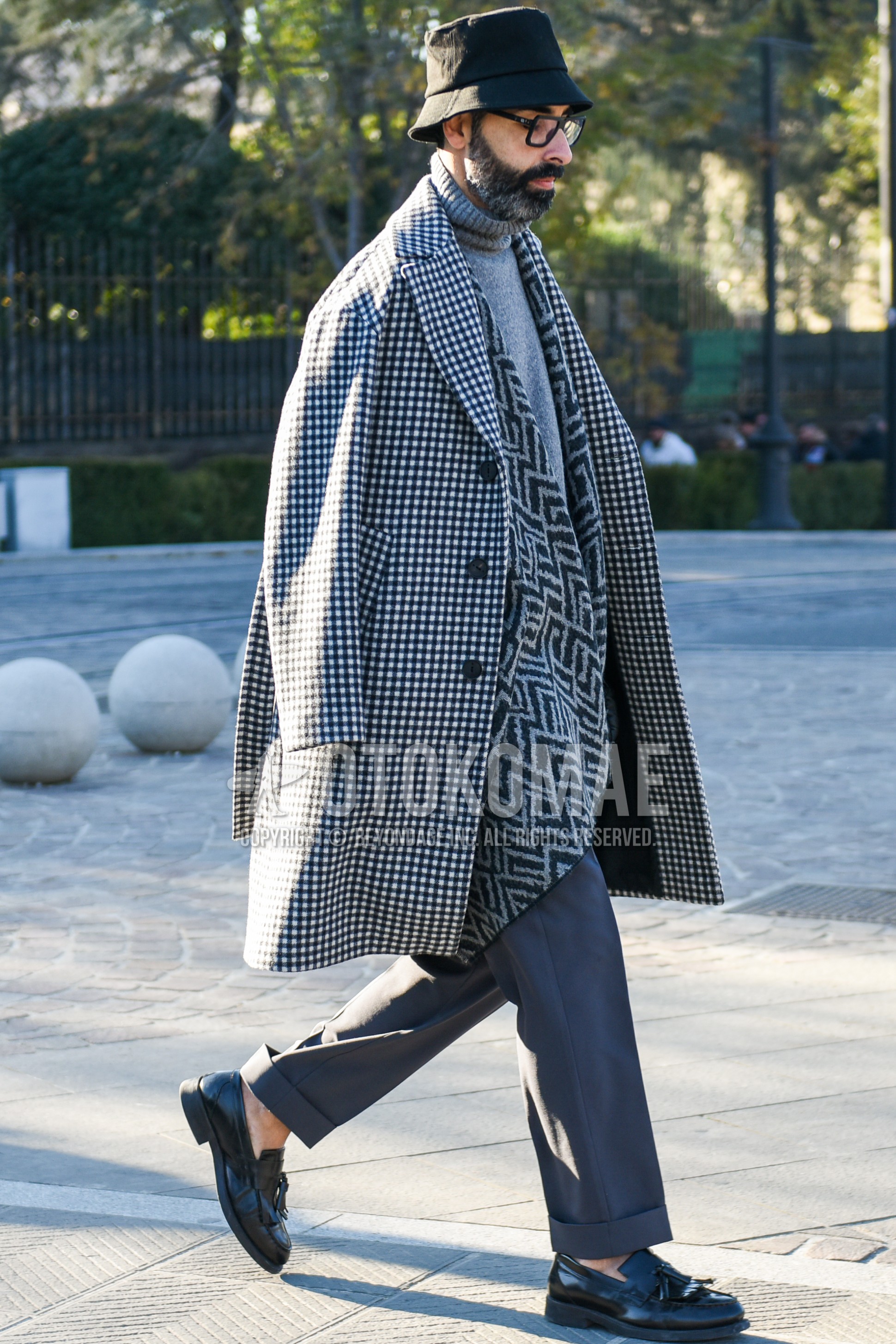 Men's autumn winter outfit with black plain hat, black plain glasses, gray scarf scarf, white black check chester coat, gray plain turtleneck knit, gray plain slacks, gray plain ankle pants, black tassel loafers leather shoes.