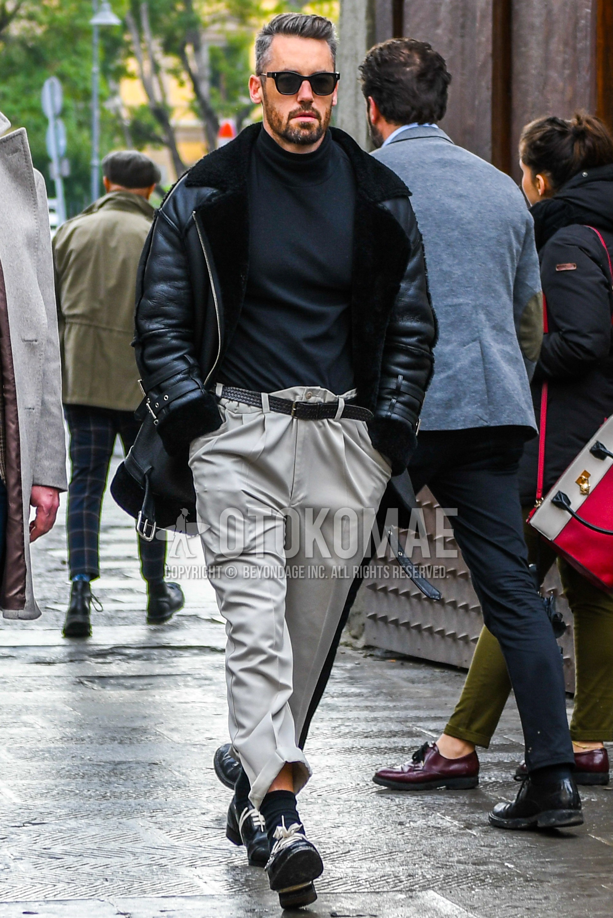 Men's autumn winter outfit with plain sunglasses, black plain leather jacket, gray plain turtleneck knit, black plain leather belt, beige plain chinos, black plain socks, black  leather shoes.