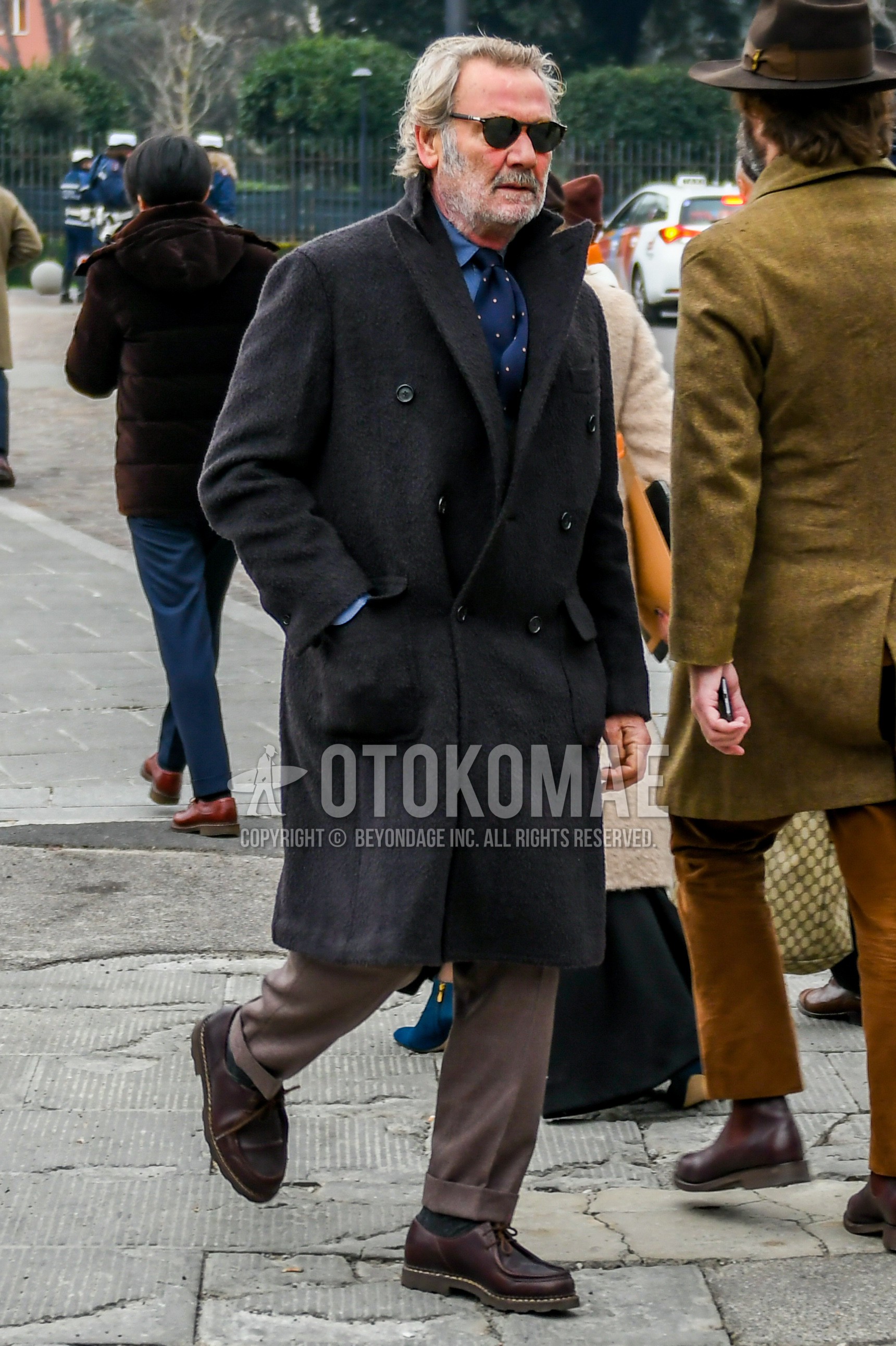 Men's autumn winter outfit with brown tortoiseshell sunglasses, dark gray plain chester coat, blue plain shirt, beige plain slacks, brown u-tip shoes leather shoes, navy dots necktie.