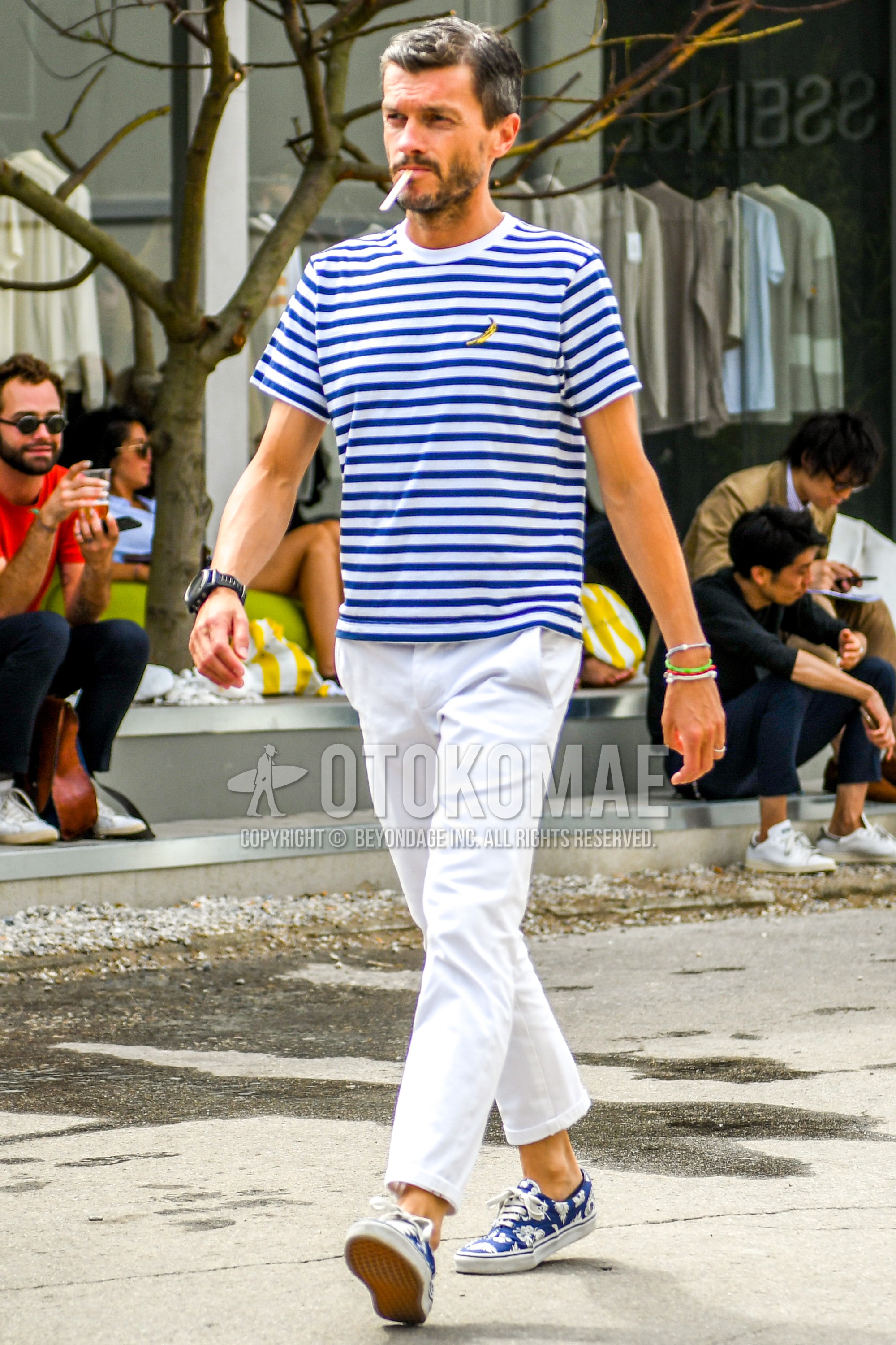Men's summer outfit with blue white horizontal stripes t-shirt, white plain ankle pants, white plain cotton pants, blue low-cut sneakers.