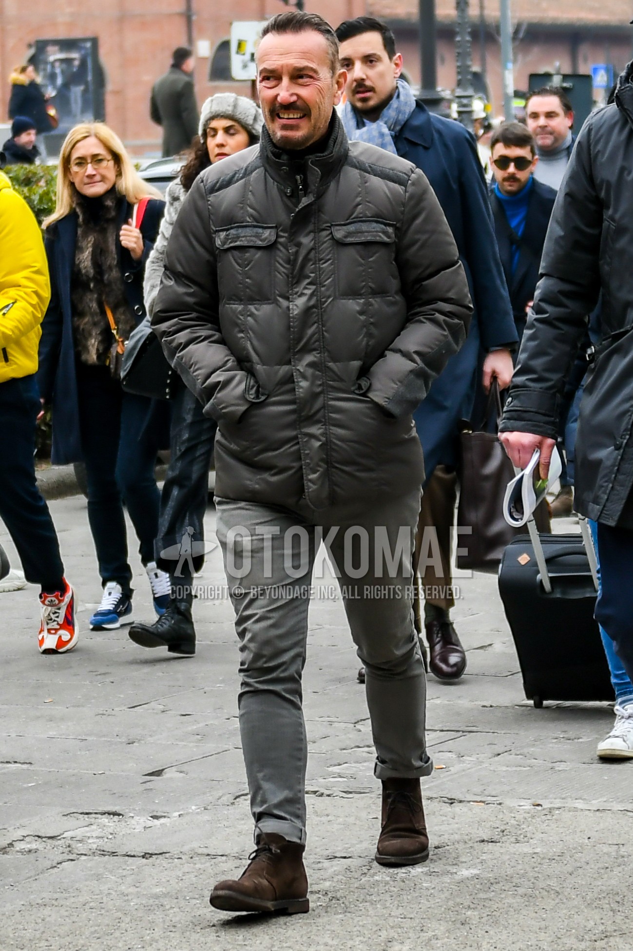Men's winter outfit with gray plain down jacket, gray plain denim/jeans, brown chukka boots.