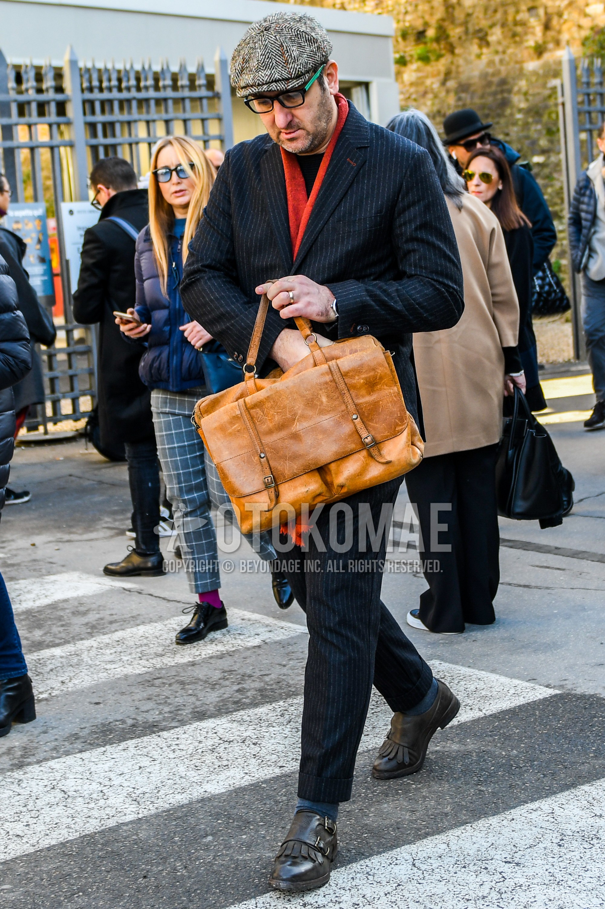 Men's winter outfit with gray herringbone cap, plain glasses, red plain scarf, black plain sweater, dark gray plain socks, black monk shoes leather shoes, brown plain briefcase/handbag, plain suit.