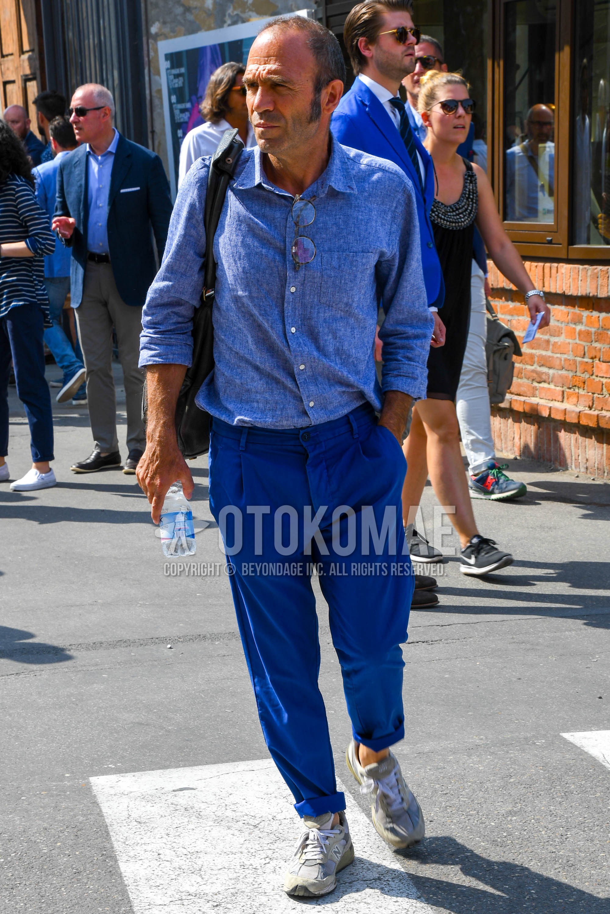 Men's spring summer autumn outfit with blue plain shirt, blue plain pleated pants, plain chinos, gray low-cut sneakers.