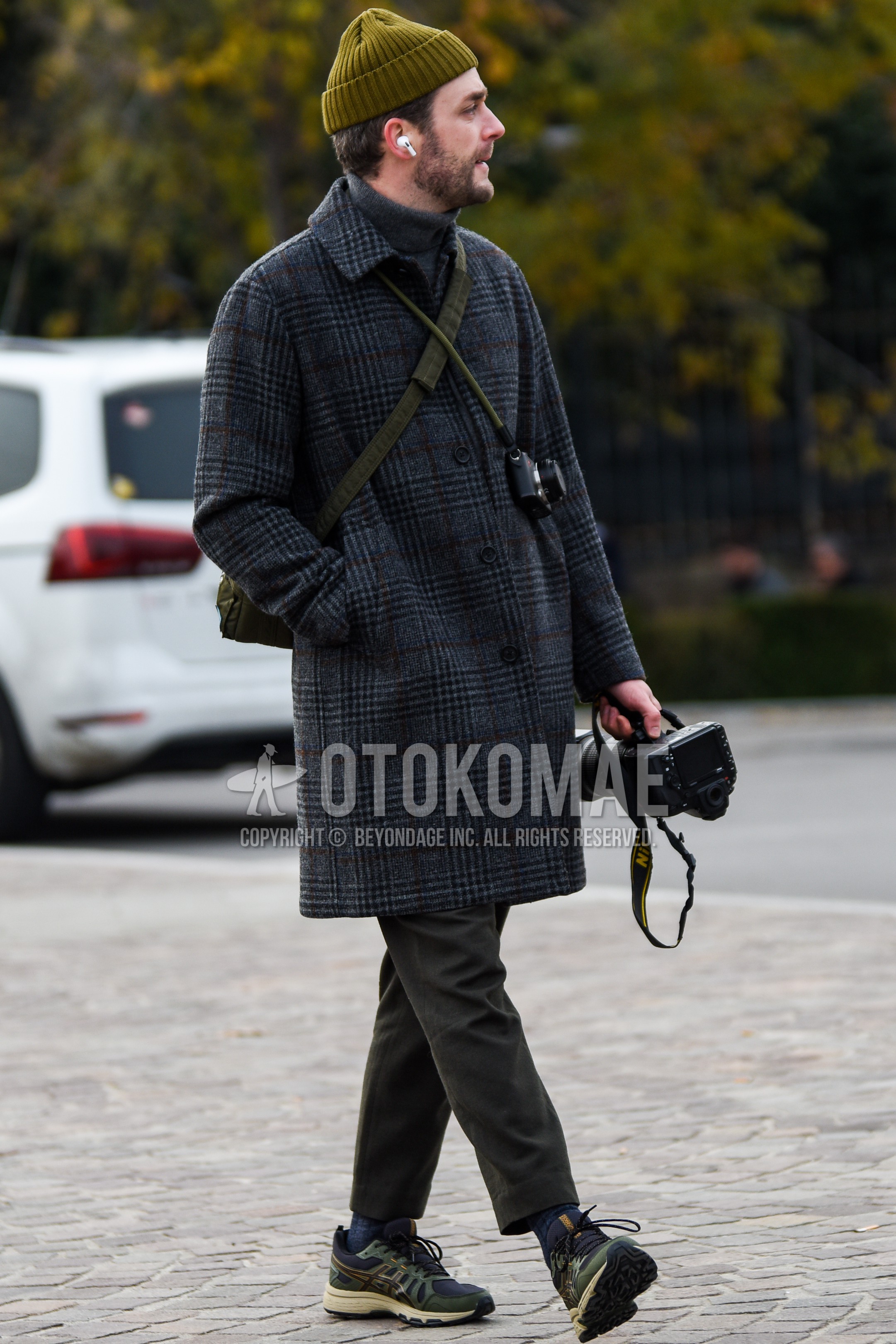 Men's autumn winter outfit with olive green plain knit cap, gray check stenkarrer coat, gray plain turtleneck knit, gray plain slacks, gray plain socks, olive green low-cut sneakers, olive green plain shoulder bag.